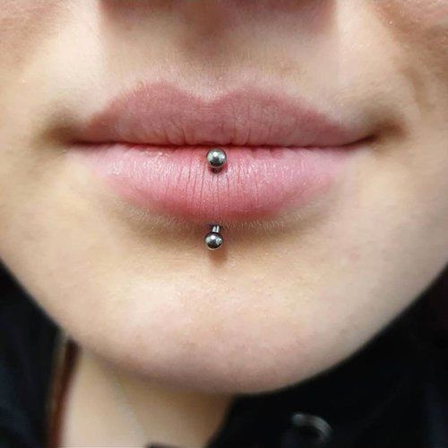 A close up of a woman 's lips with a lip piercing.