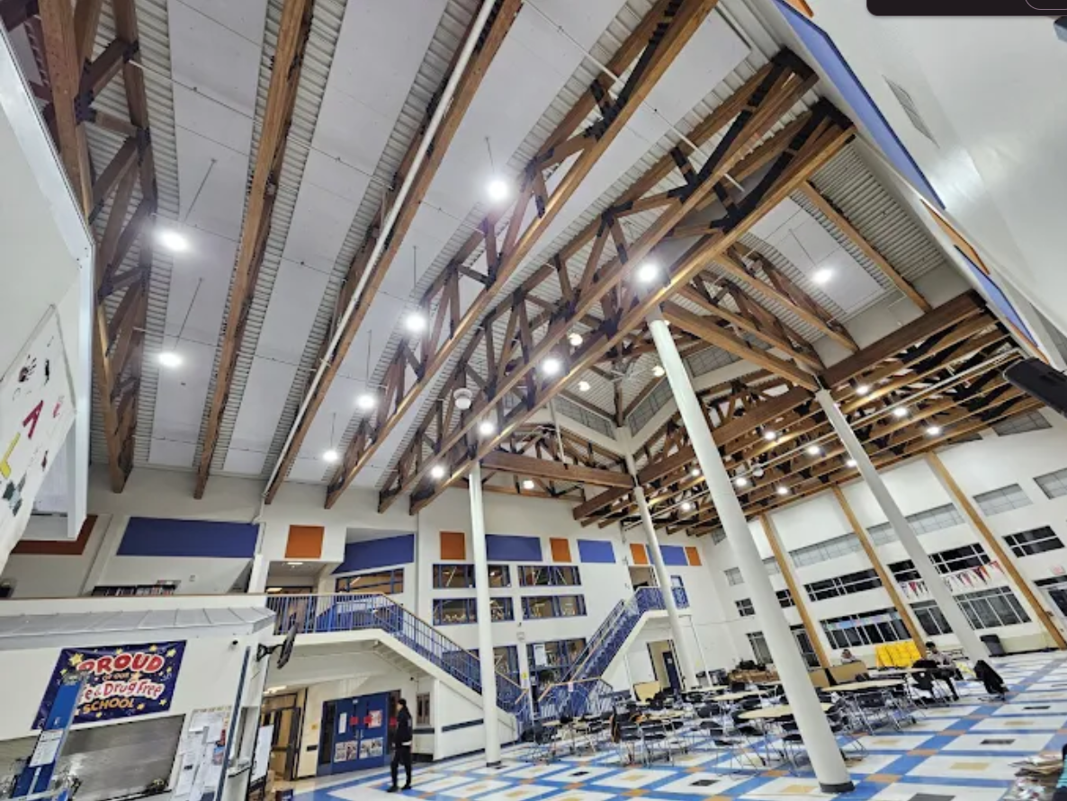 Interior of a modern airport terminal with high wooden ceiling, pillars, and rows of empty seating