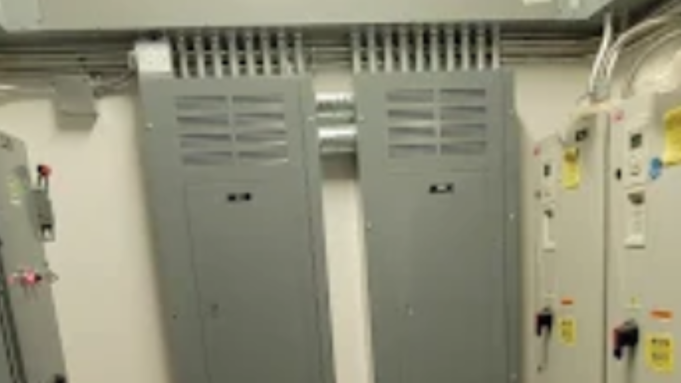 Electrical room with gray control cabinets and wall-mounted switches.
