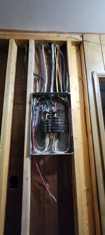 Open electrical panel with exposed wires in a wall cavity during construction