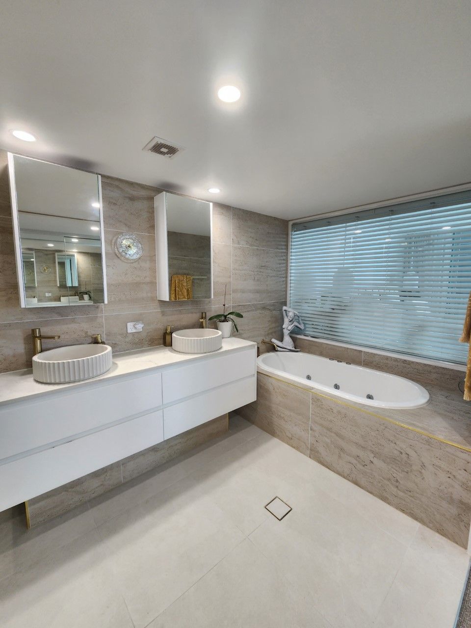 A bathroom with two sinks , a tub and a mirror.