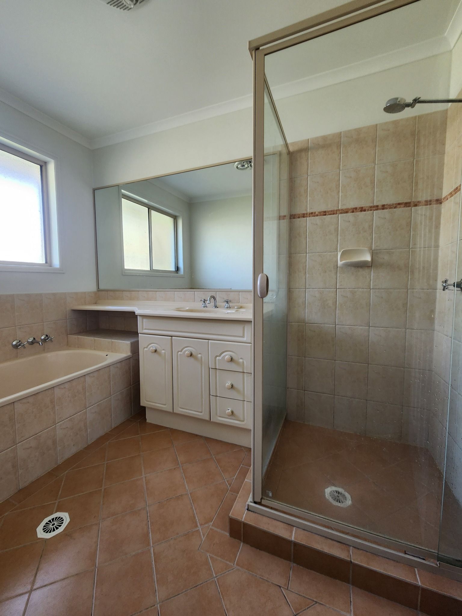A bathroom with a tub , sink , shower and mirror.