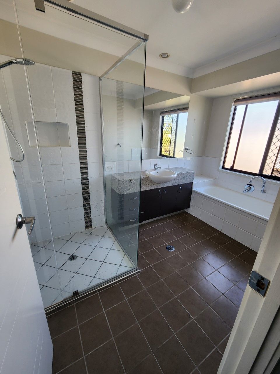 A bathroom with a walk in shower , sink , tub and mirror.