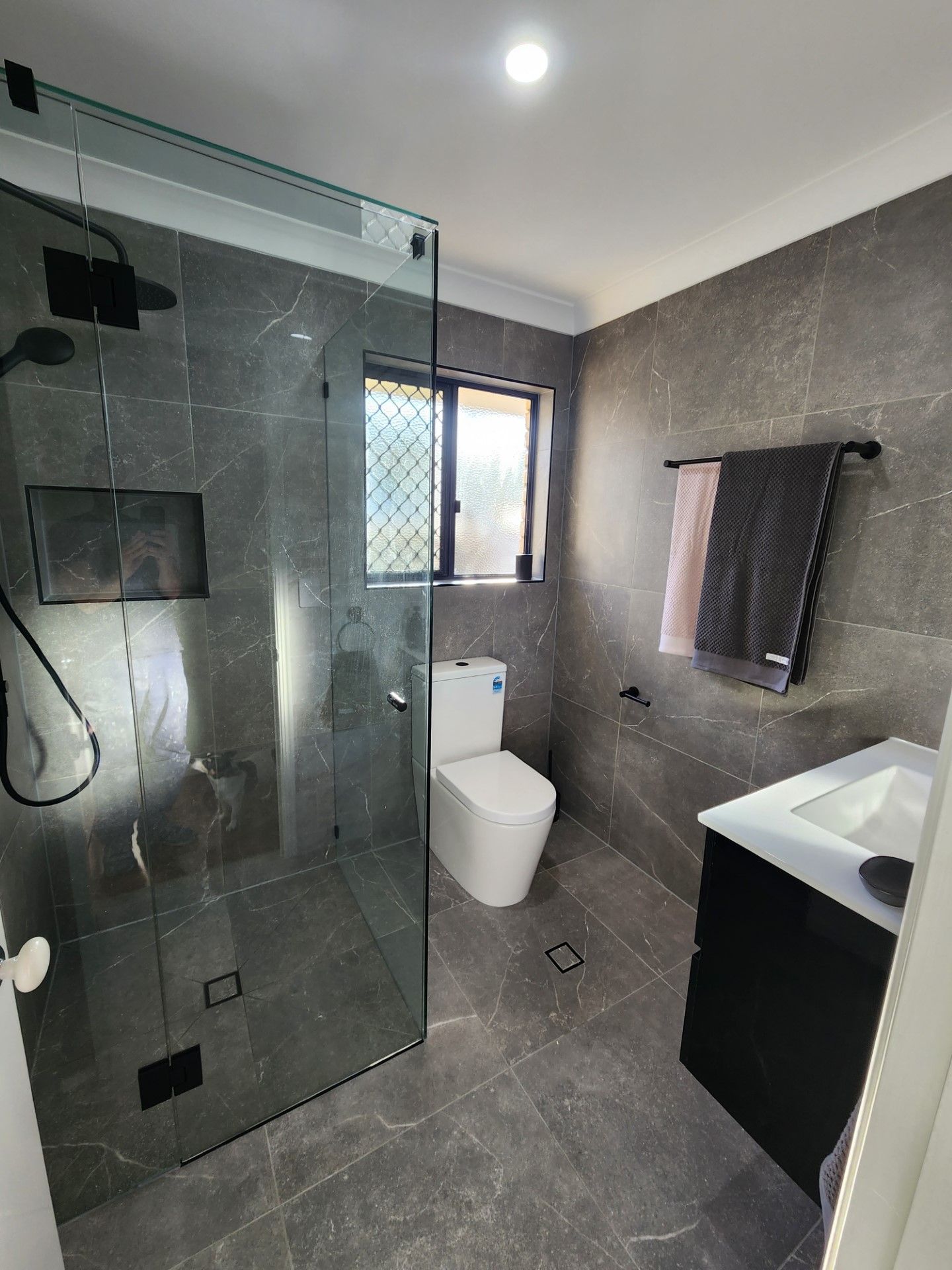 A bathroom with a toilet , sink and shower.