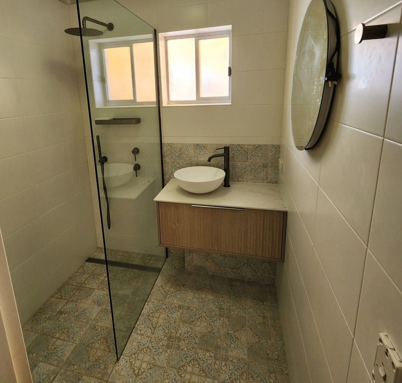A bathroom with a sink , shower , and mirror.