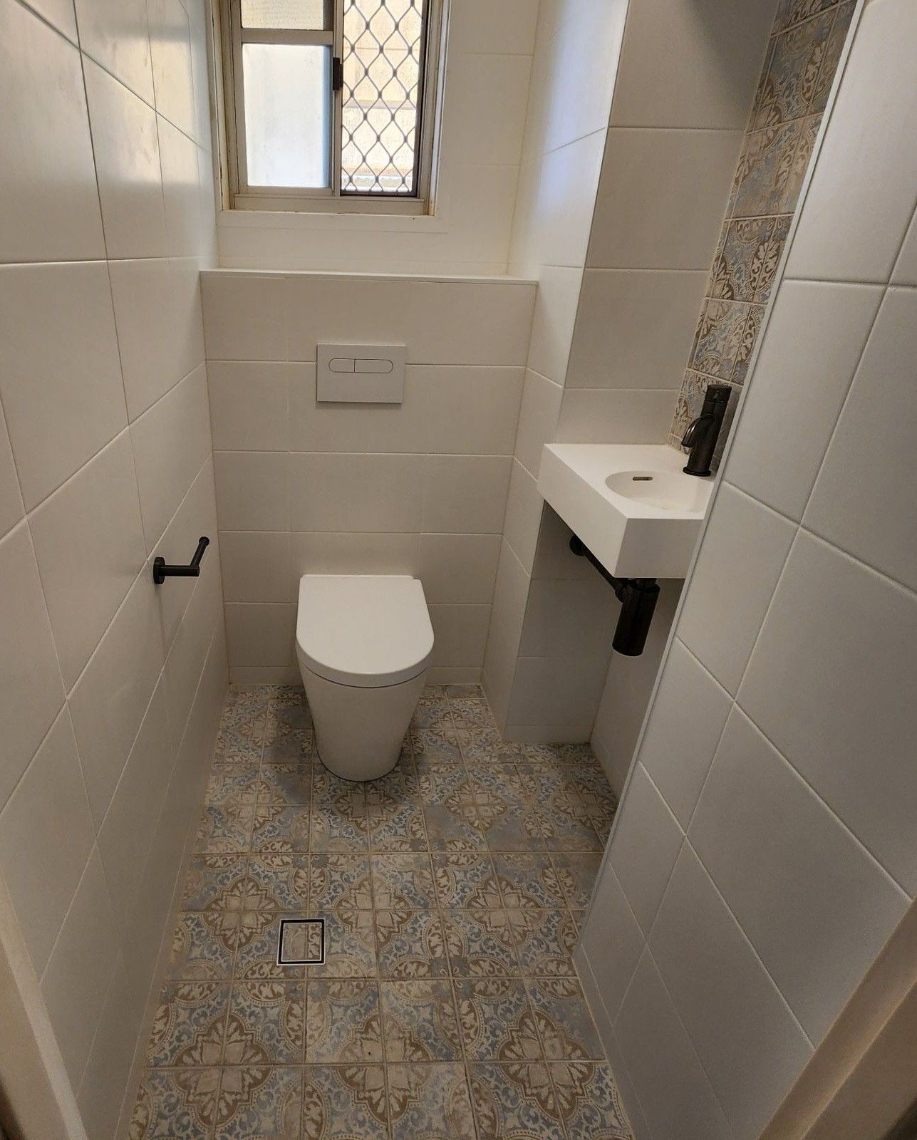 A bathroom with a toilet , sink and window.