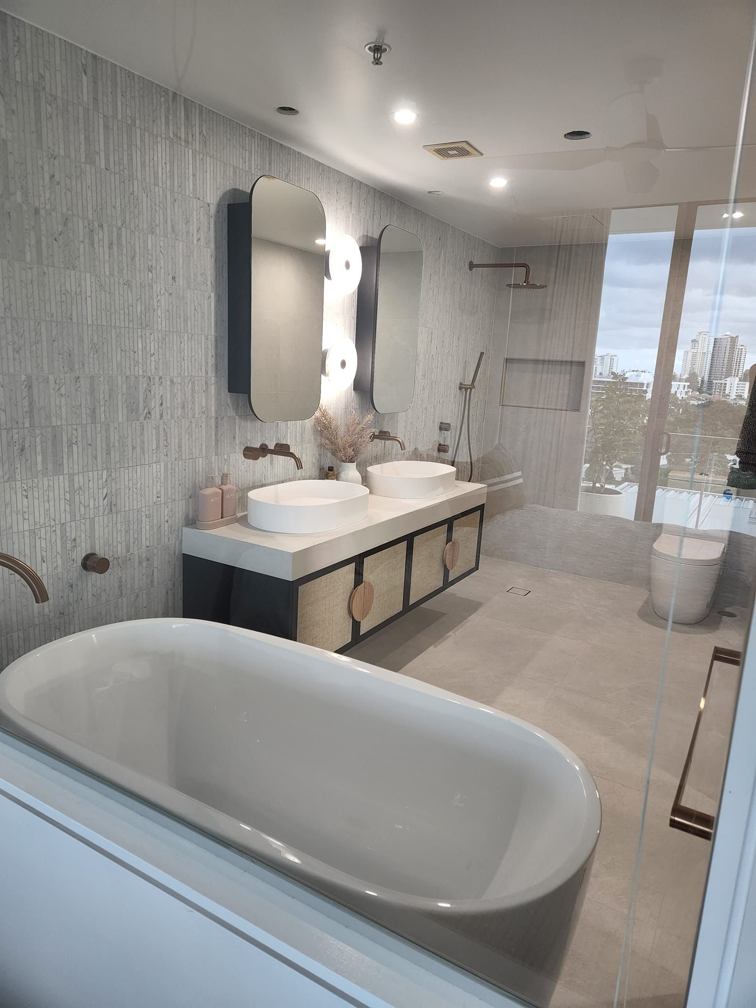 A bathroom with two sinks , a tub , a toilet and a mirror.