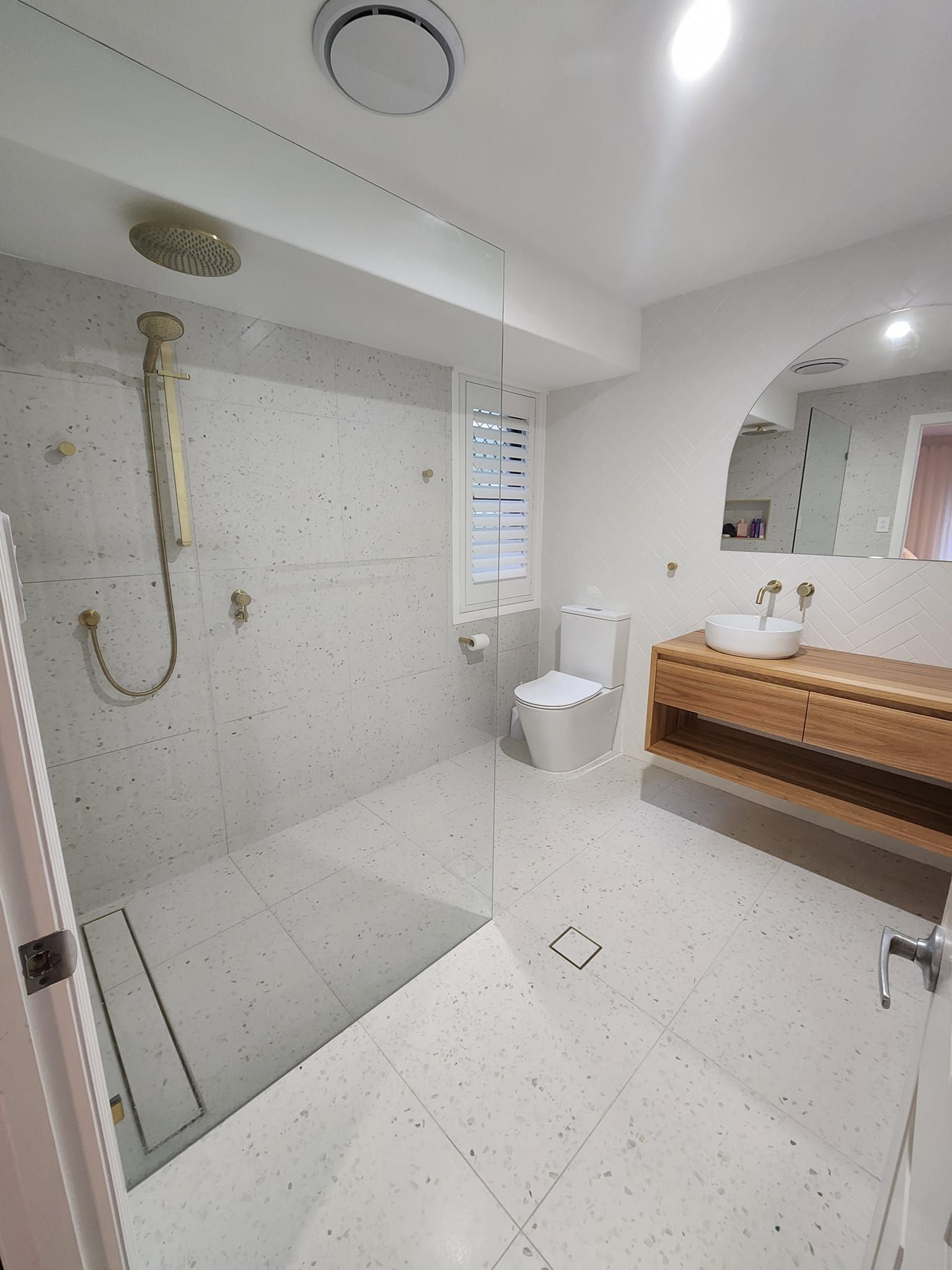 A bathroom with a walk in shower , toilet , sink and mirror.