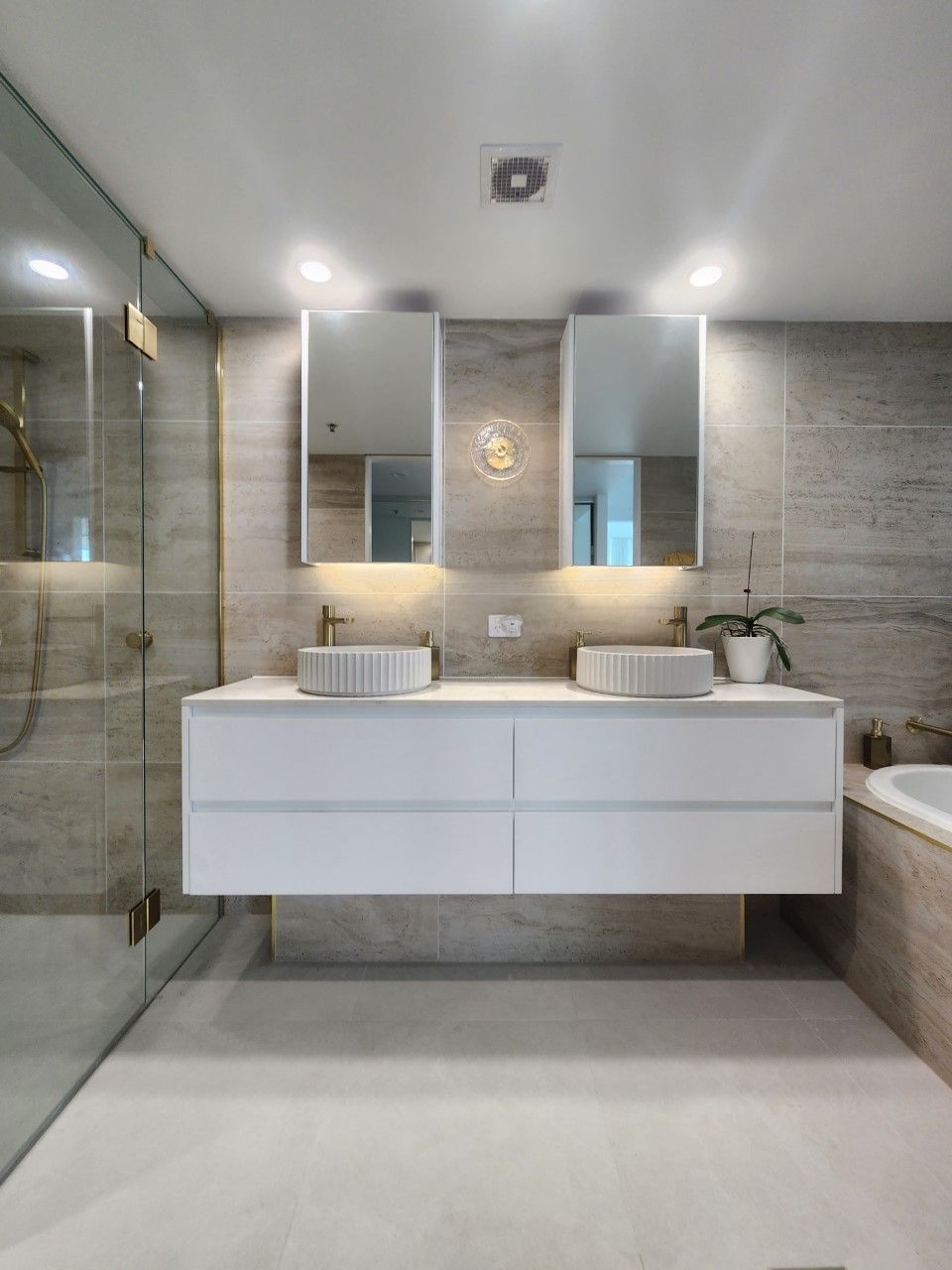 A bathroom with two sinks , two mirrors and a bathtub.
