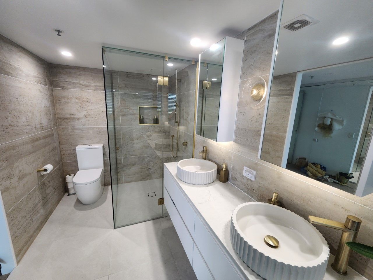 A bathroom with two sinks , a toilet and a walk in shower.