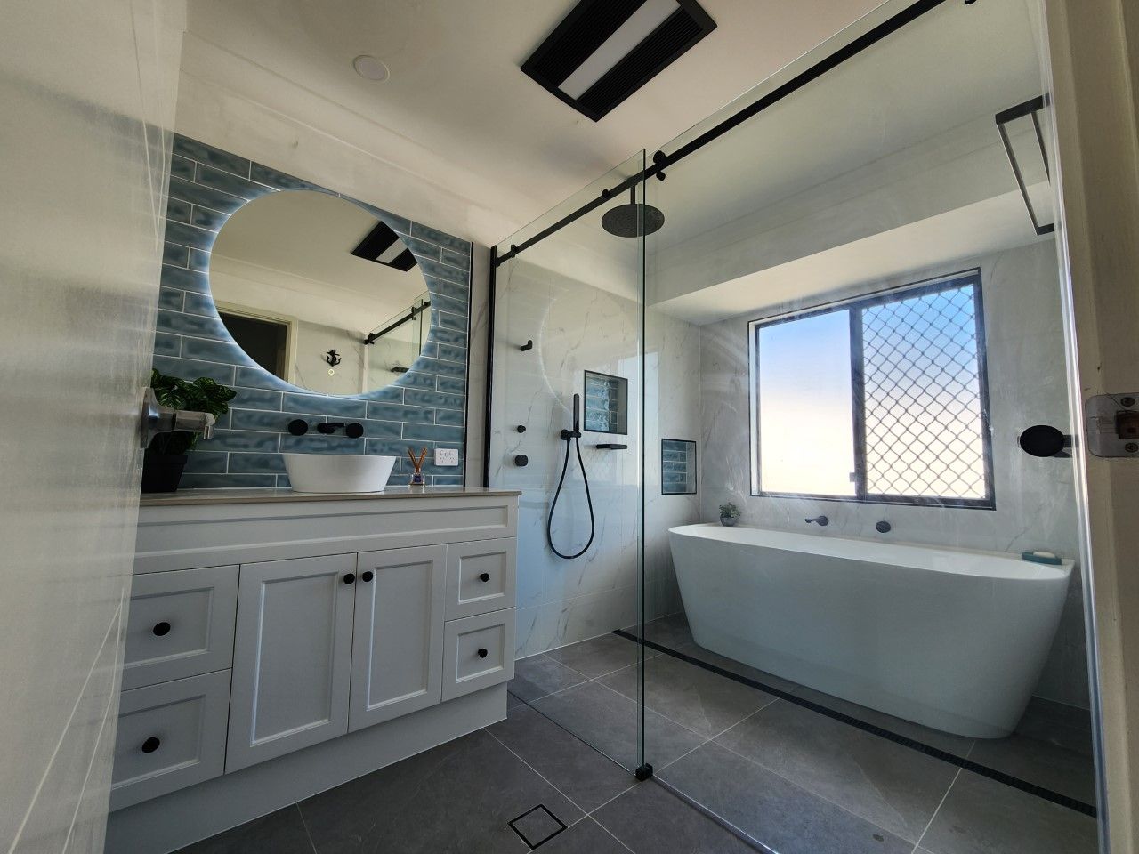 A bathroom with a tub , sink , mirror and shower.
