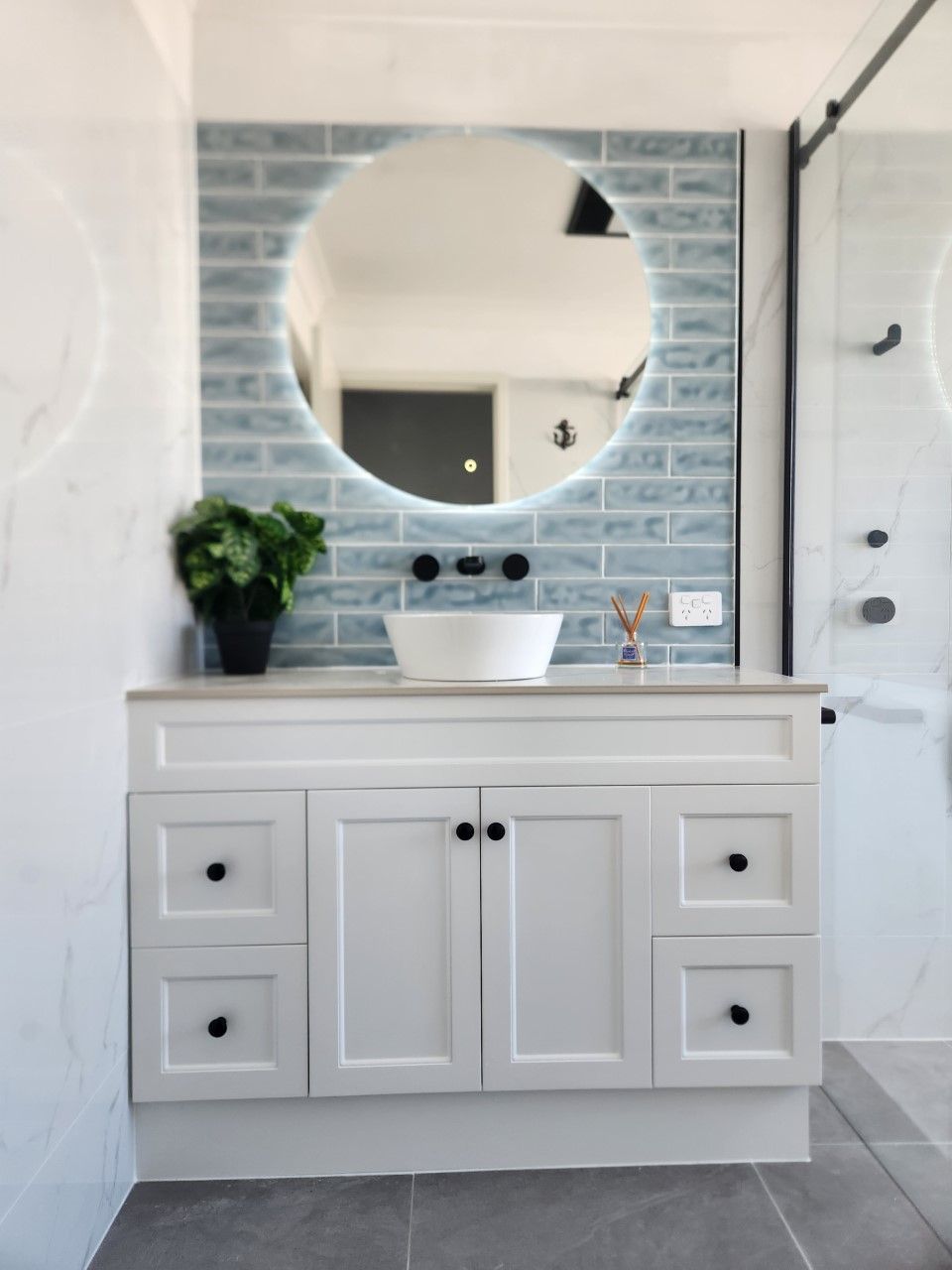 A bathroom with a sink and a round mirror