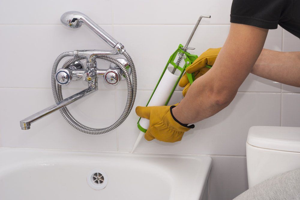 Applying Sealant To The Bathtub — Bathroom & Laundry Renovations in Coomera, QLD