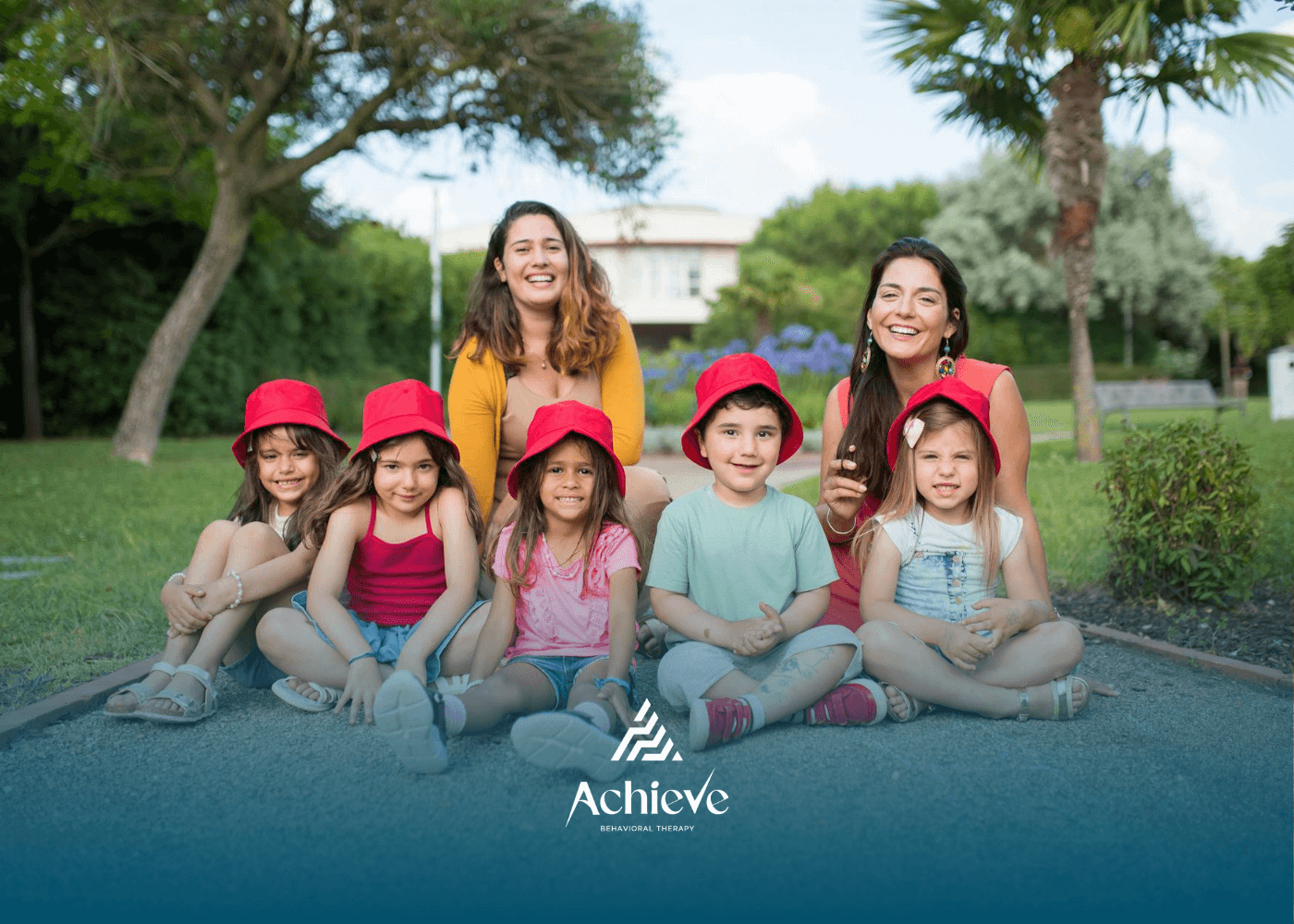 A BCBA, RBT and autistic children in red hats posing outdoors during school-based ABA therapy in NC.