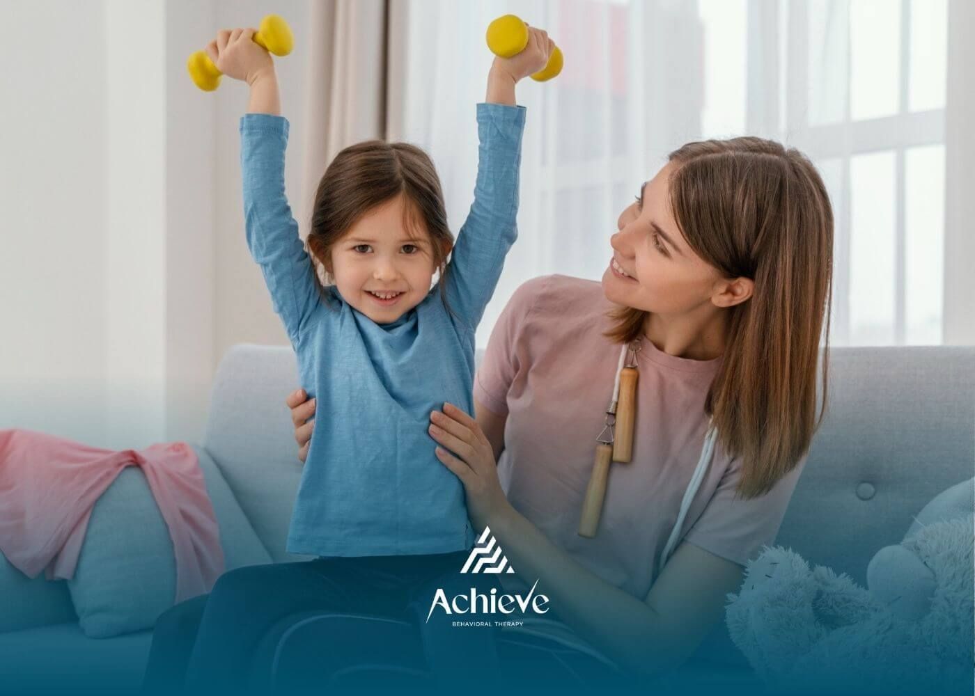 Girl lifting small yellow dumbbells with ABA therapist encouraging her in ABA therapy.