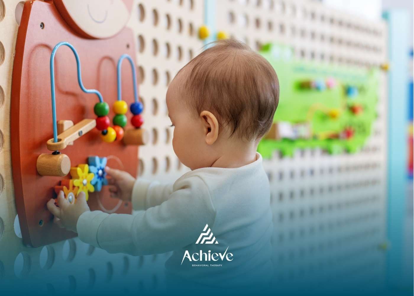 Baby playing with a wooden sensory board on a wall, colorful beads and gears.