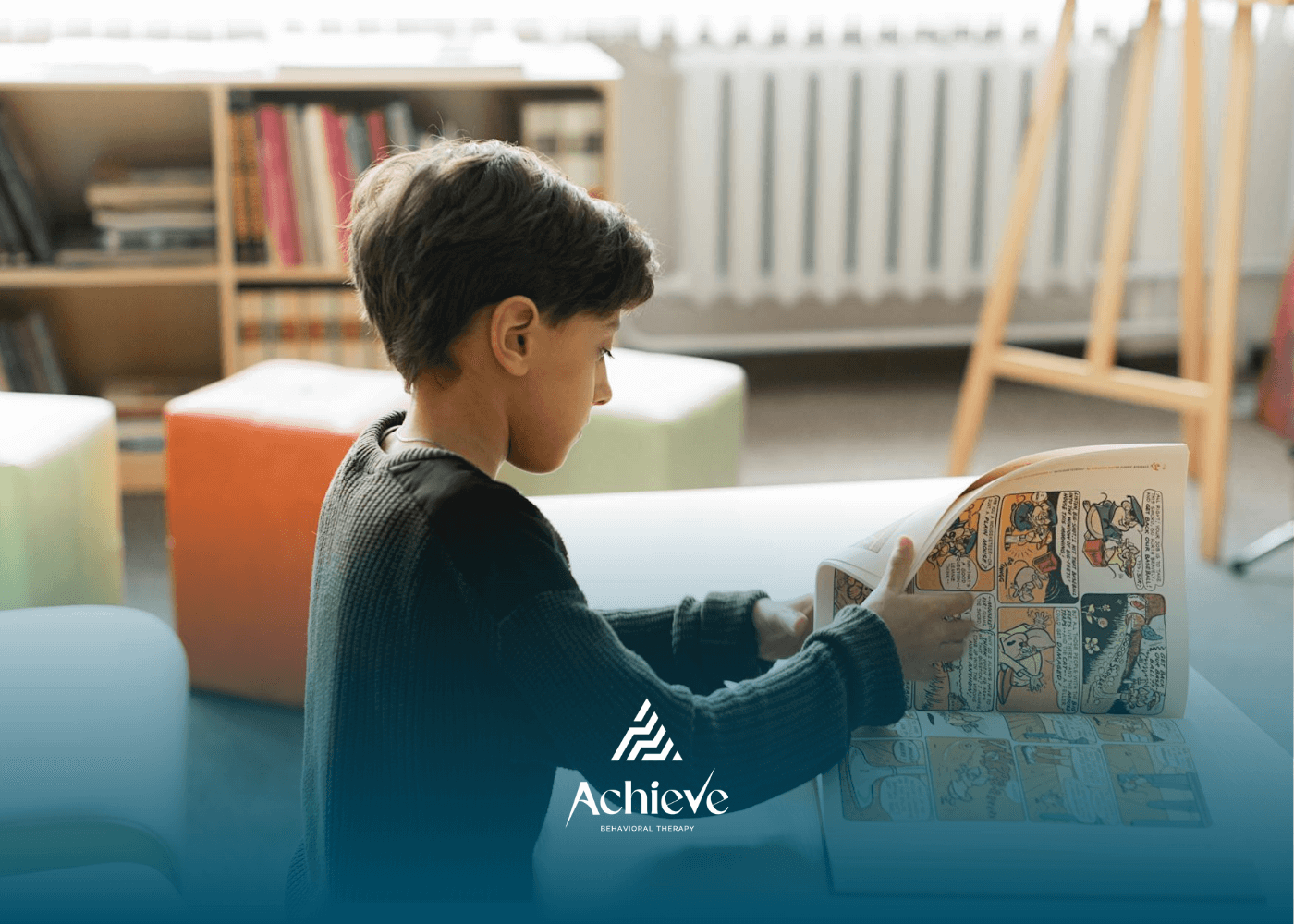 Young autistic boy reading a large comic book at table during school-based ABA therapy in NC.