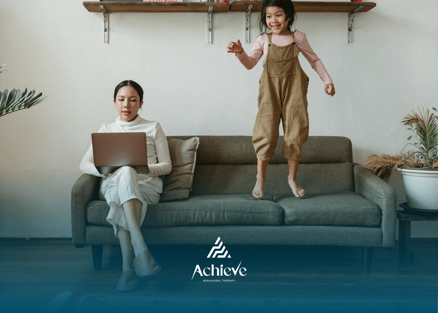 Autistic child jumping on couch while ab RBT works on laptop beside her during in-home ABA therapy.
