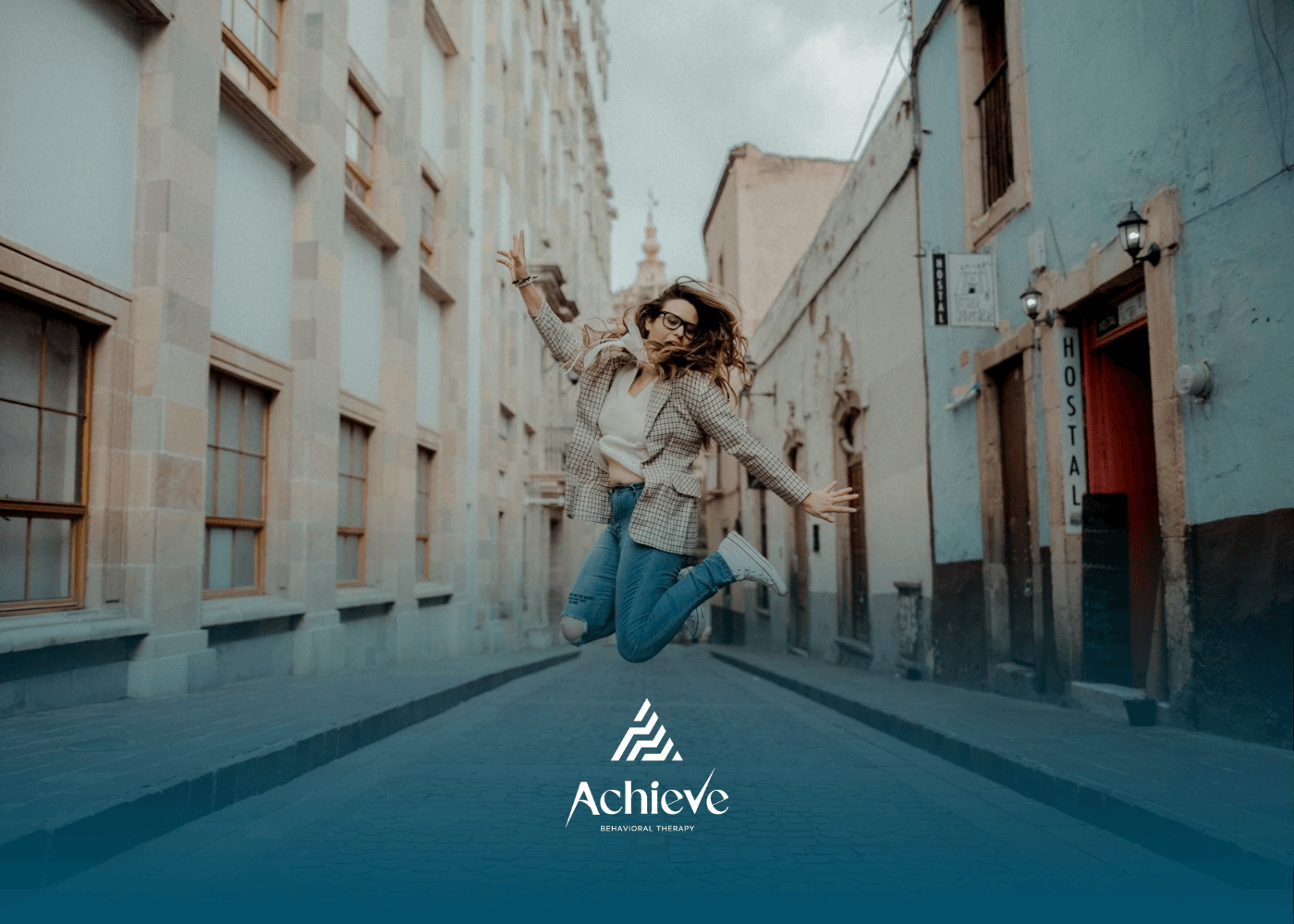 An autistic adult woman jumping joyfully in the middle of a cobblestone street in North Carolina.