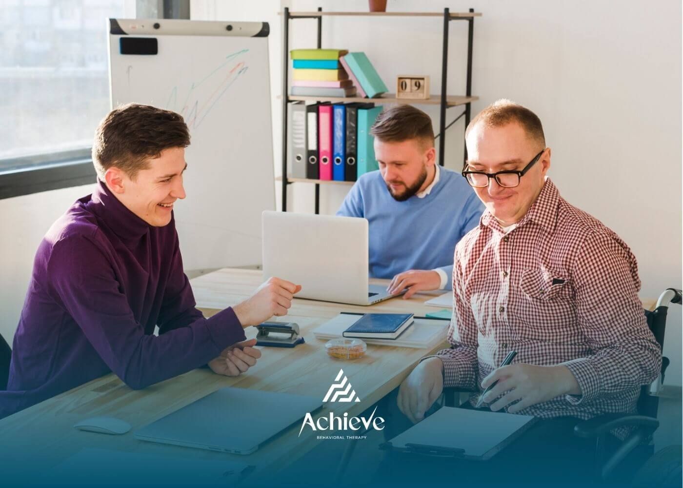 Three autistic colleagues working together in an office, collaborating over laptops and documents.