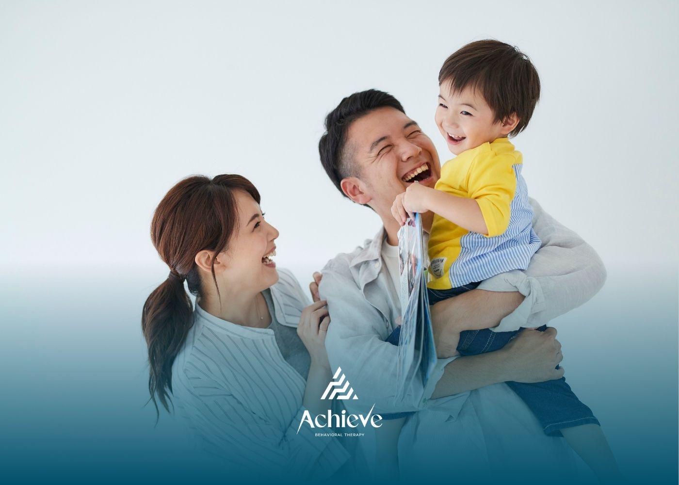 Smiling parents holding a laughing child; white background.