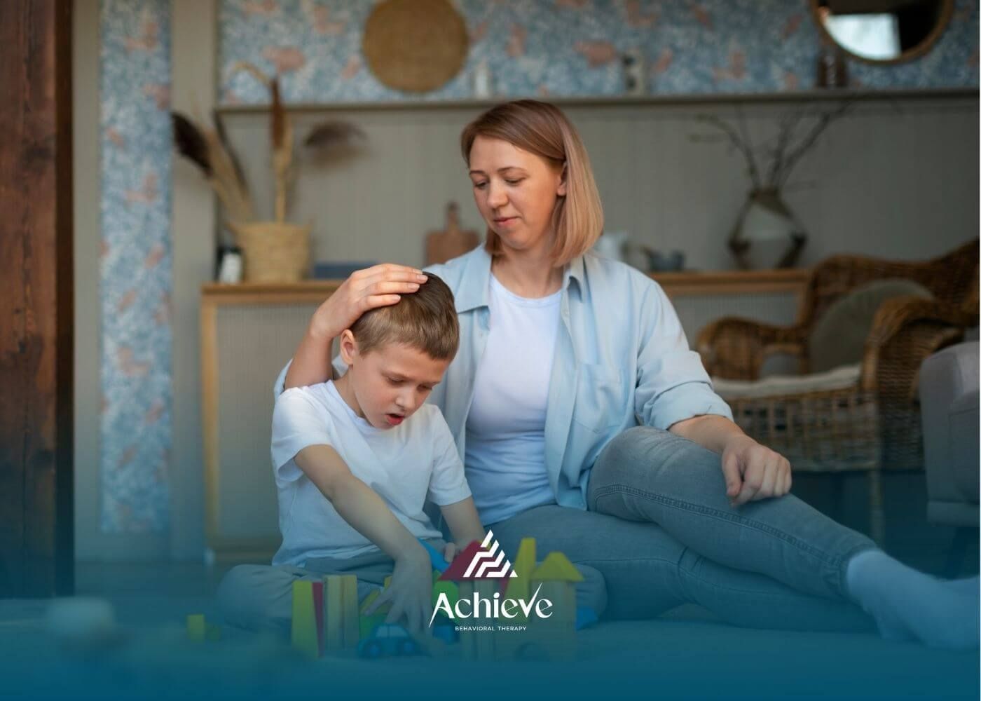 ABA therapist comforting autistic boy while playing with building blocks together on the floor.