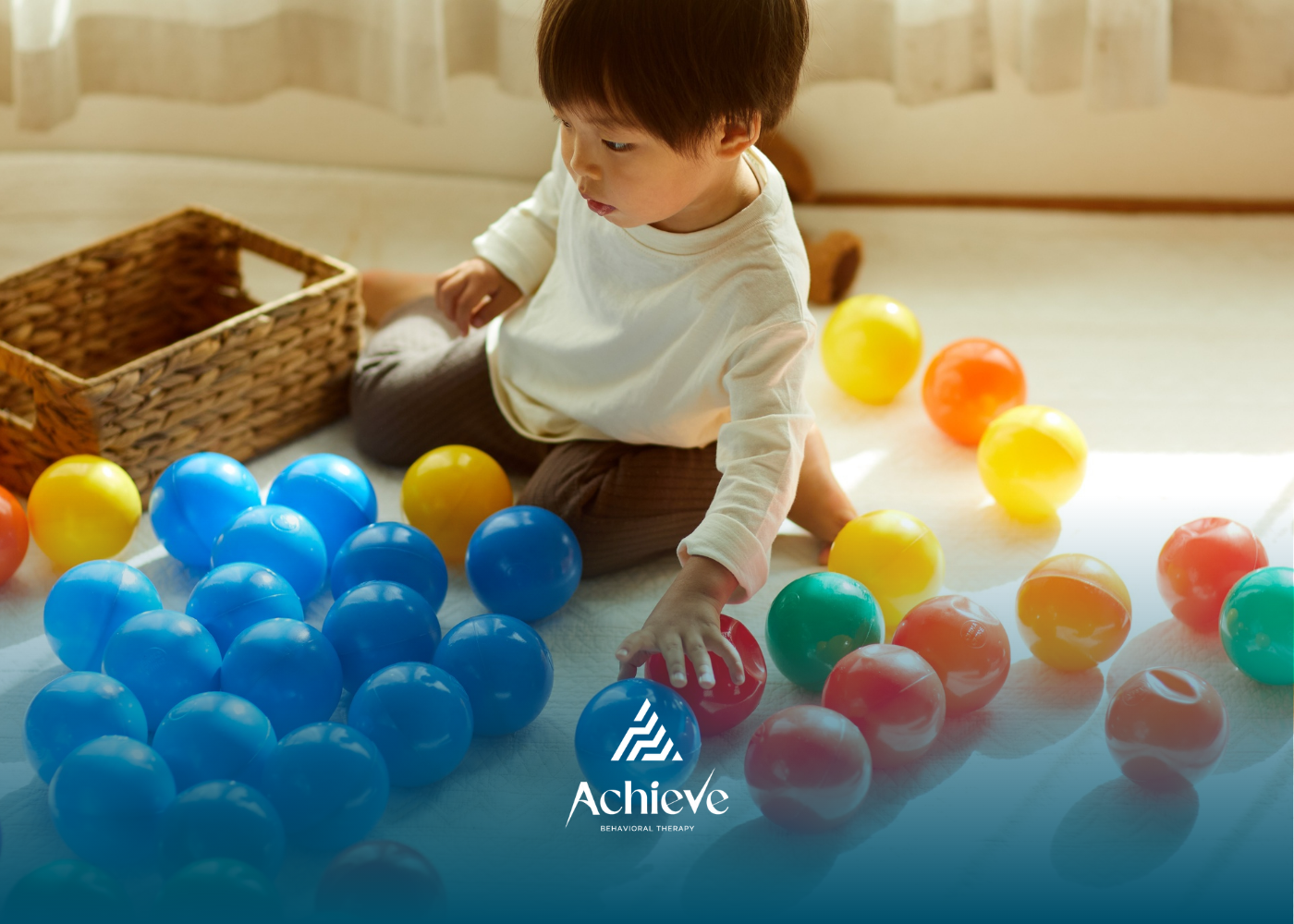 Toddler playing with colorful plastic balls indoors beside a wicker basket