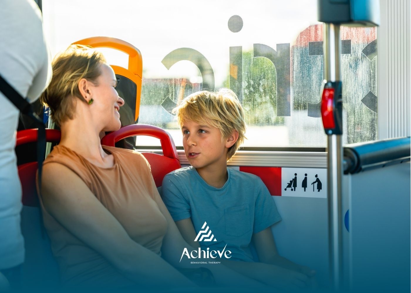 A person and a child seated together on a bus, conversing and looking at each other, with an 