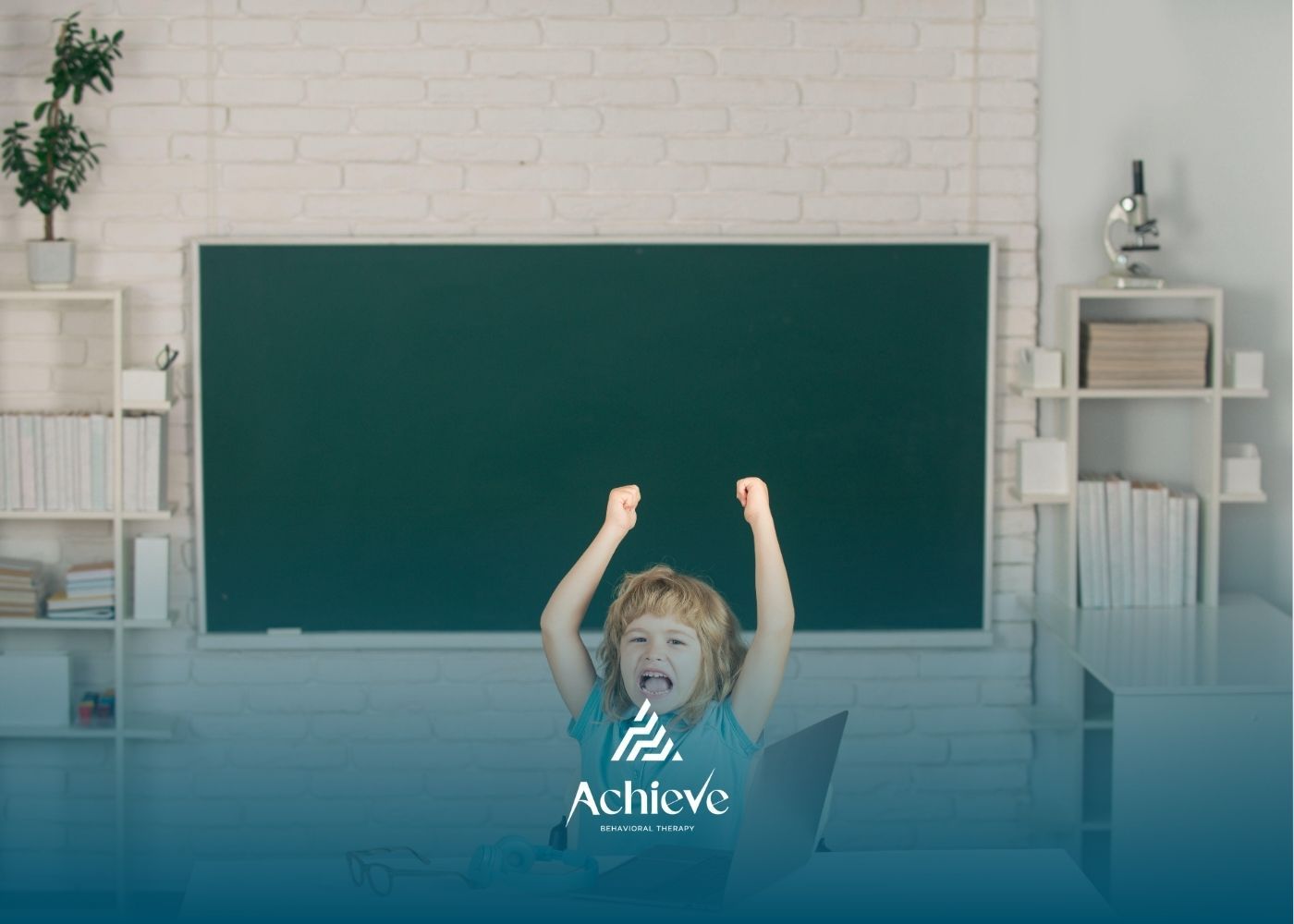 Child with raised arms and excited expression in front of a chalkboard.