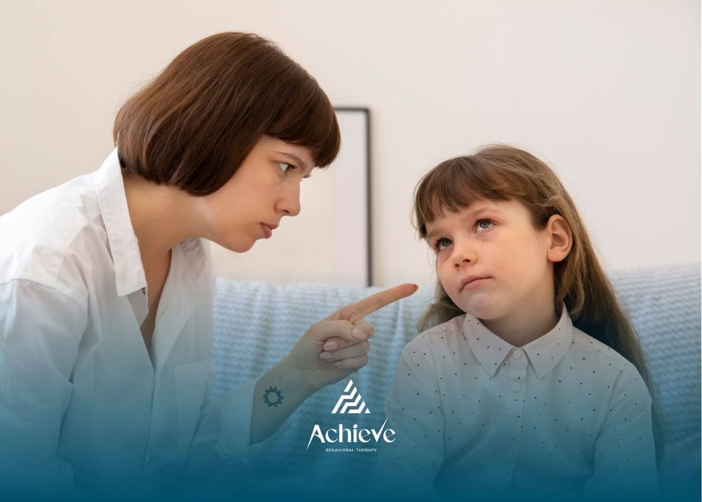 ABA therapist scolding autistic girl with a finger-pointing gesture as the girl looks away.