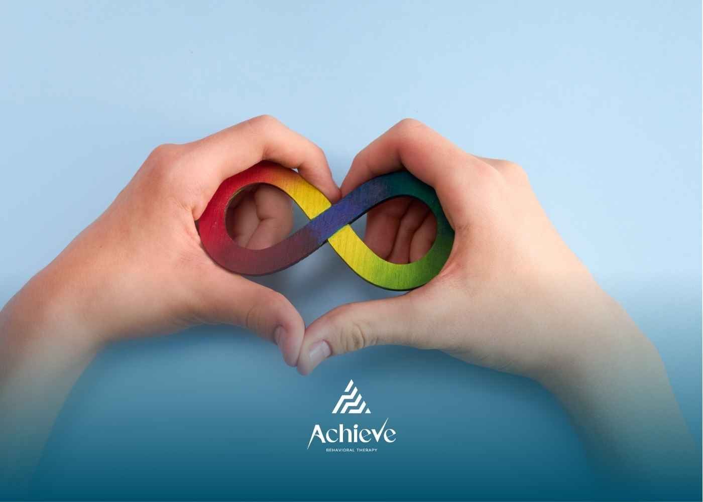 Two hands holding a multicolored infinity symbol on a light blue background.
