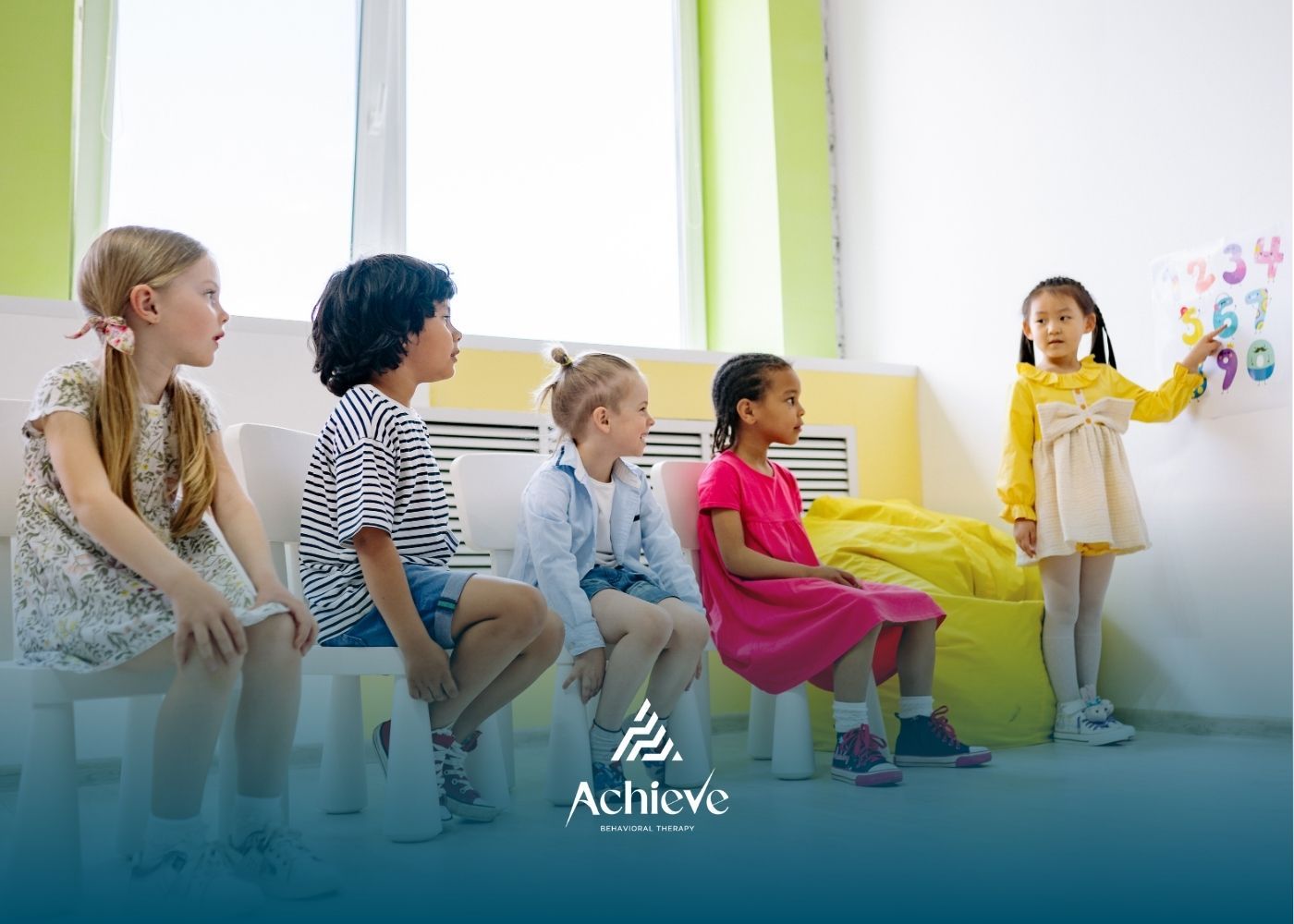 Children in a classroom looking at numbers. A girl points at numbers on a chart.