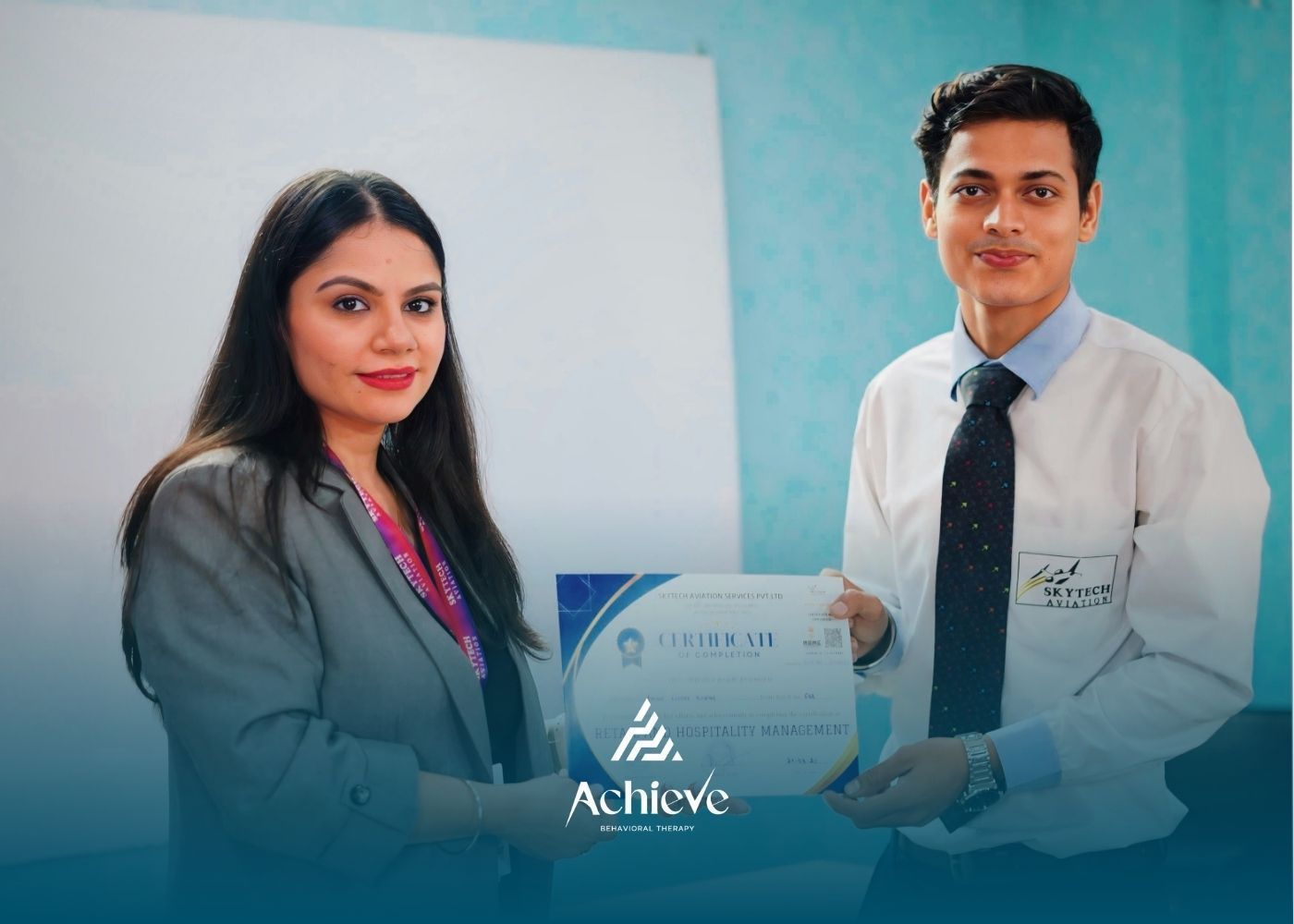 Man and woman hold a certificate for completing Retail and Hospitality Management curriculum.