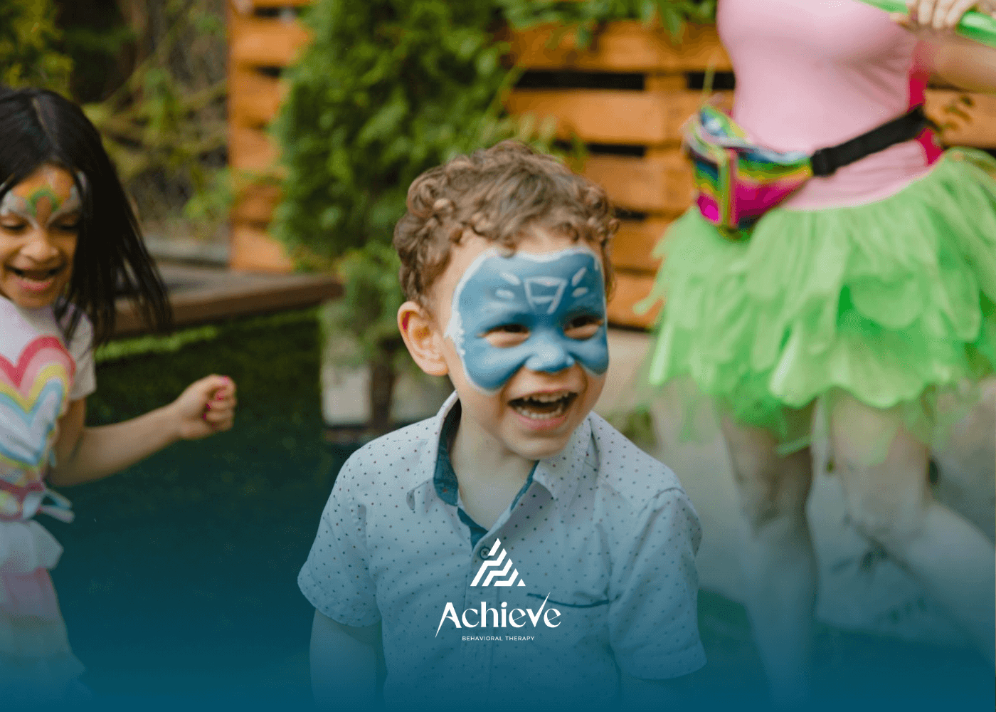 Smiling autistic boy with face paint playing outdoors with friends during ABA therapy in New Jersey.