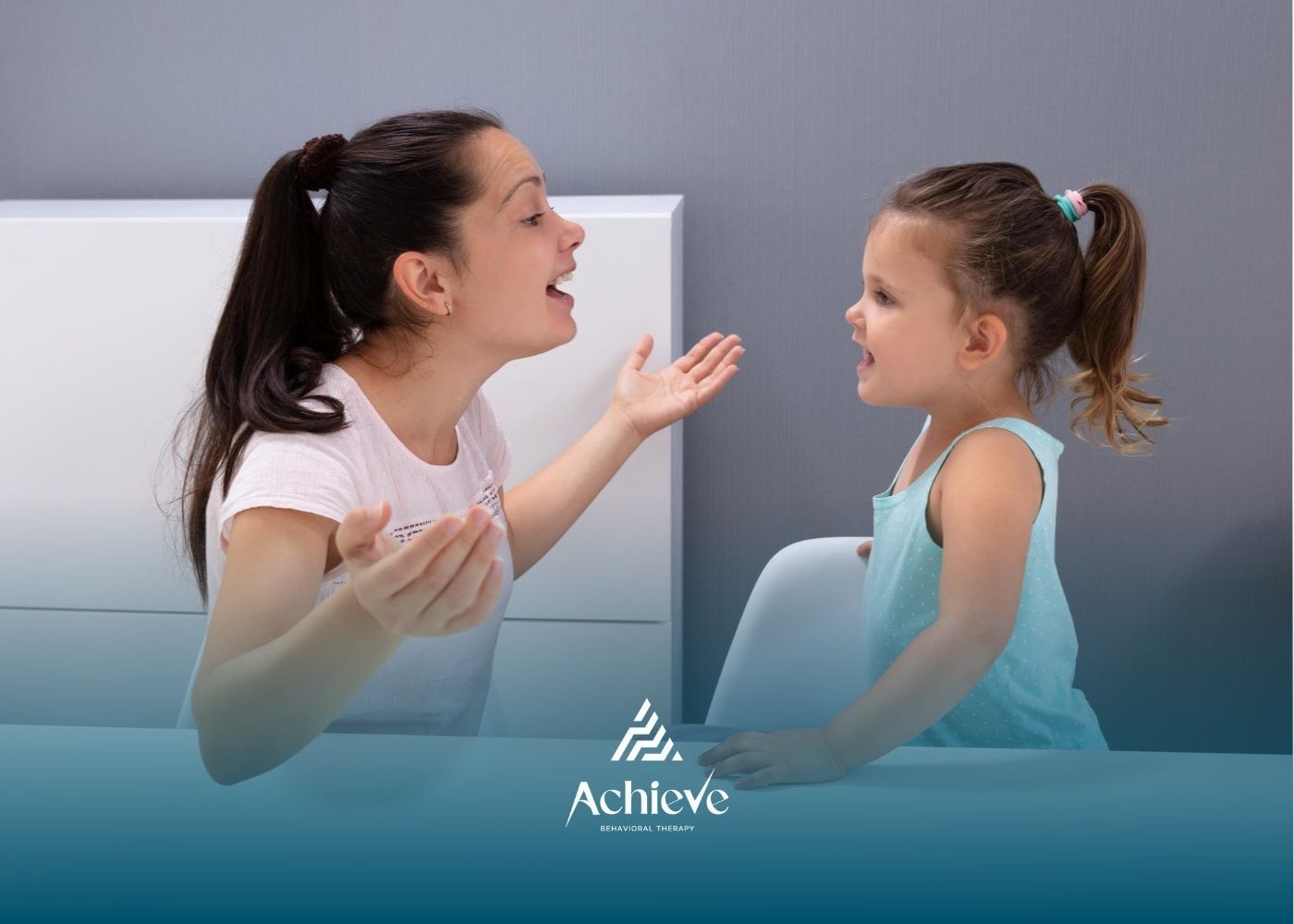 ABA therapist helping a young child with autism practice communication skills at a table,