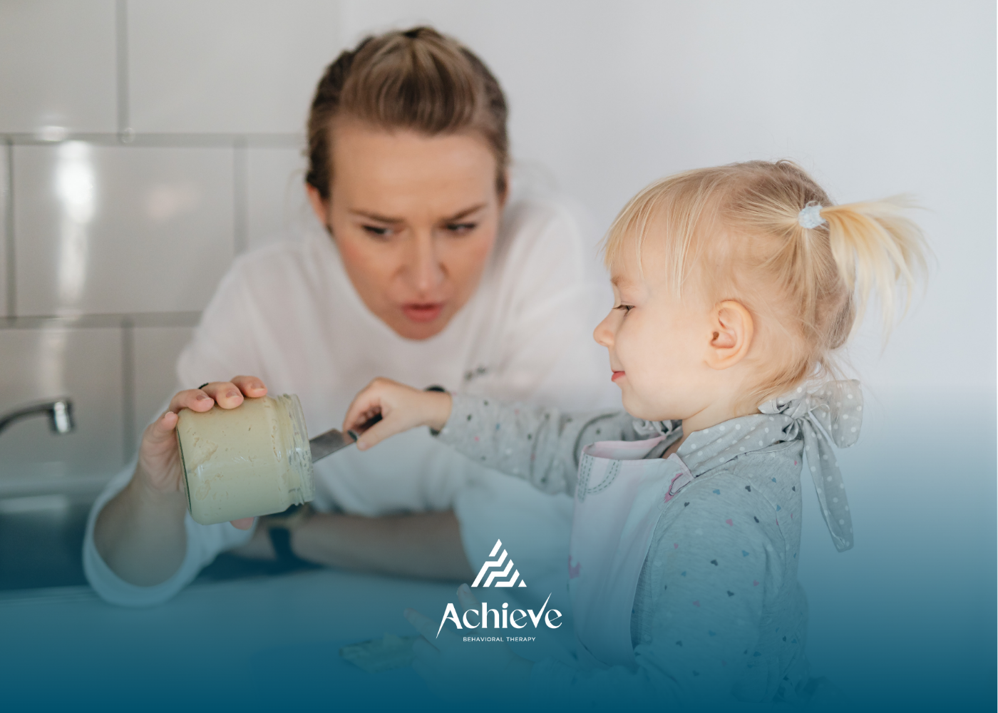 Woman and toddler scooping from jar in kitchen.