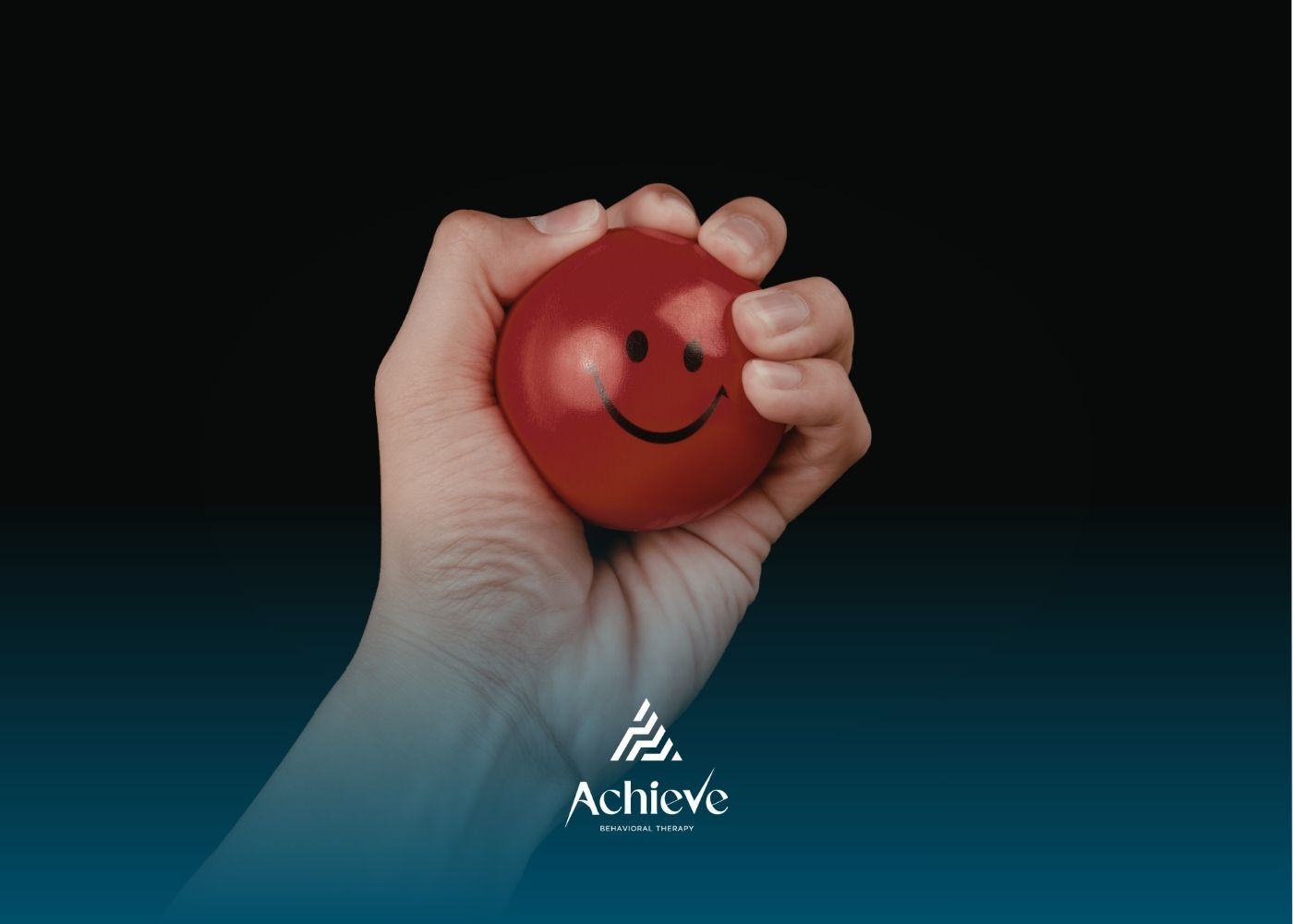 Hand squeezing a red stress ball with a smiley face.