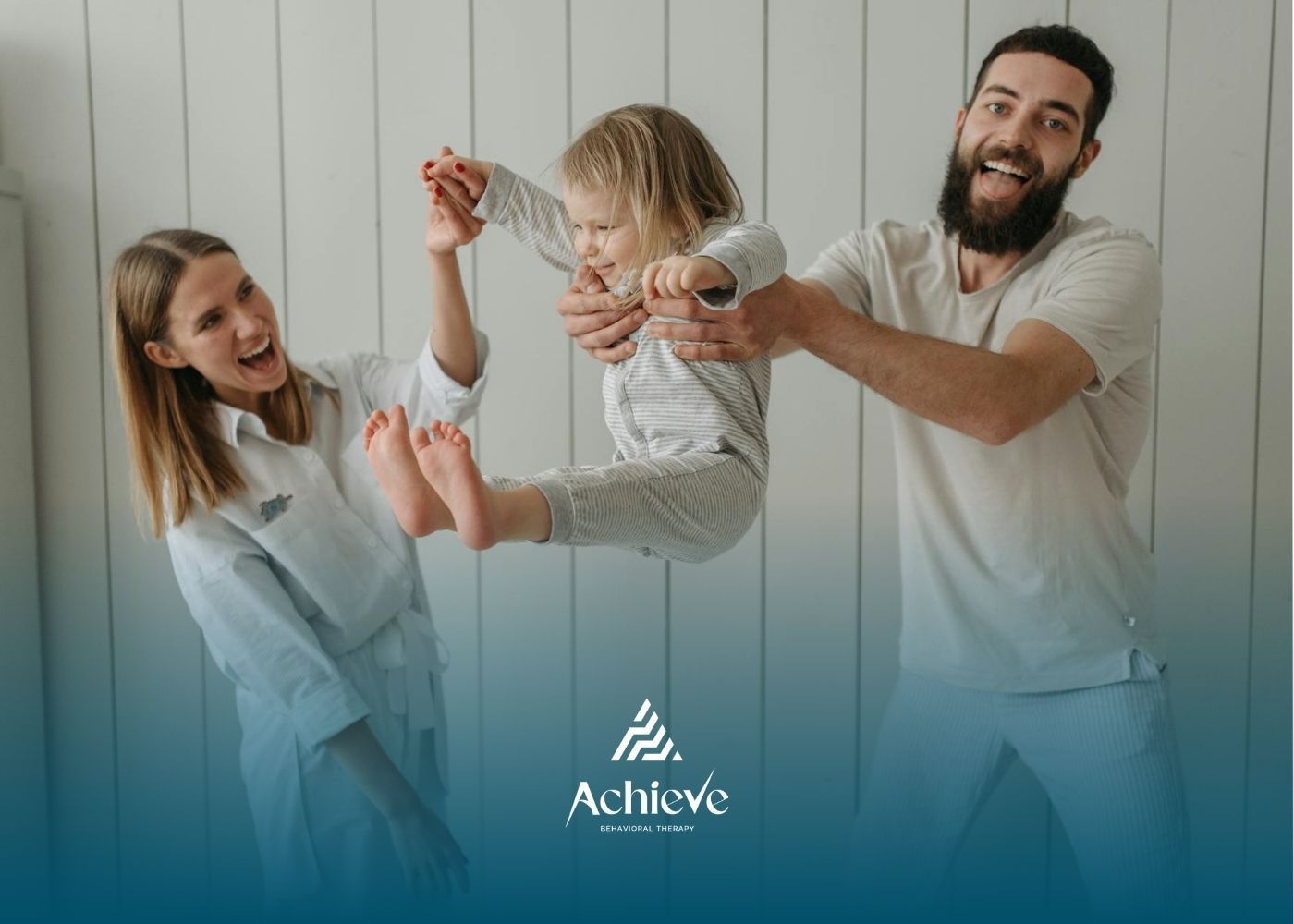 Two ABA therapist lift a smiling child indoors during playful family interaction after ABA therapy.