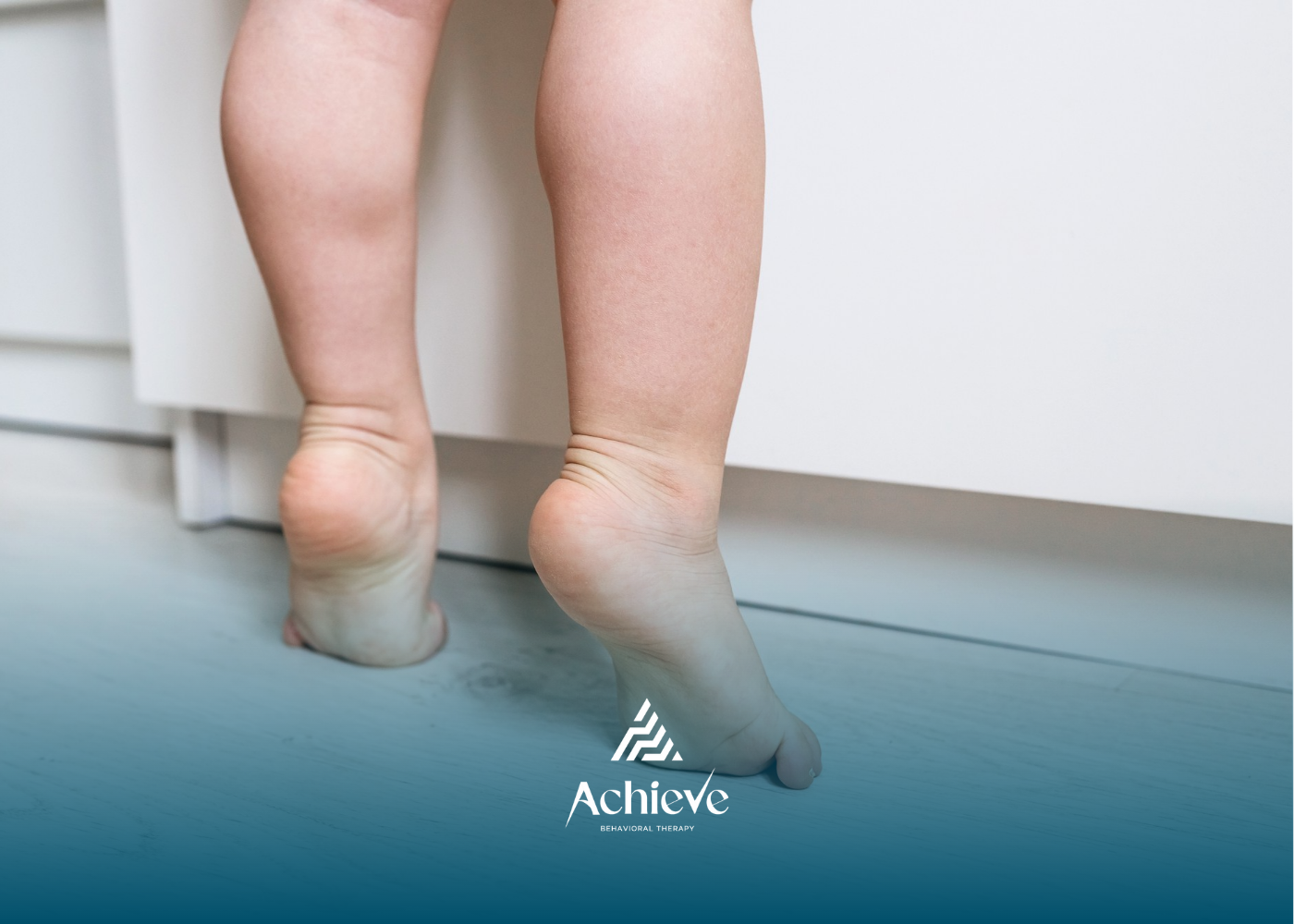 Bare feet of a child standing on tiptoes, reaching toward a white cabinet.