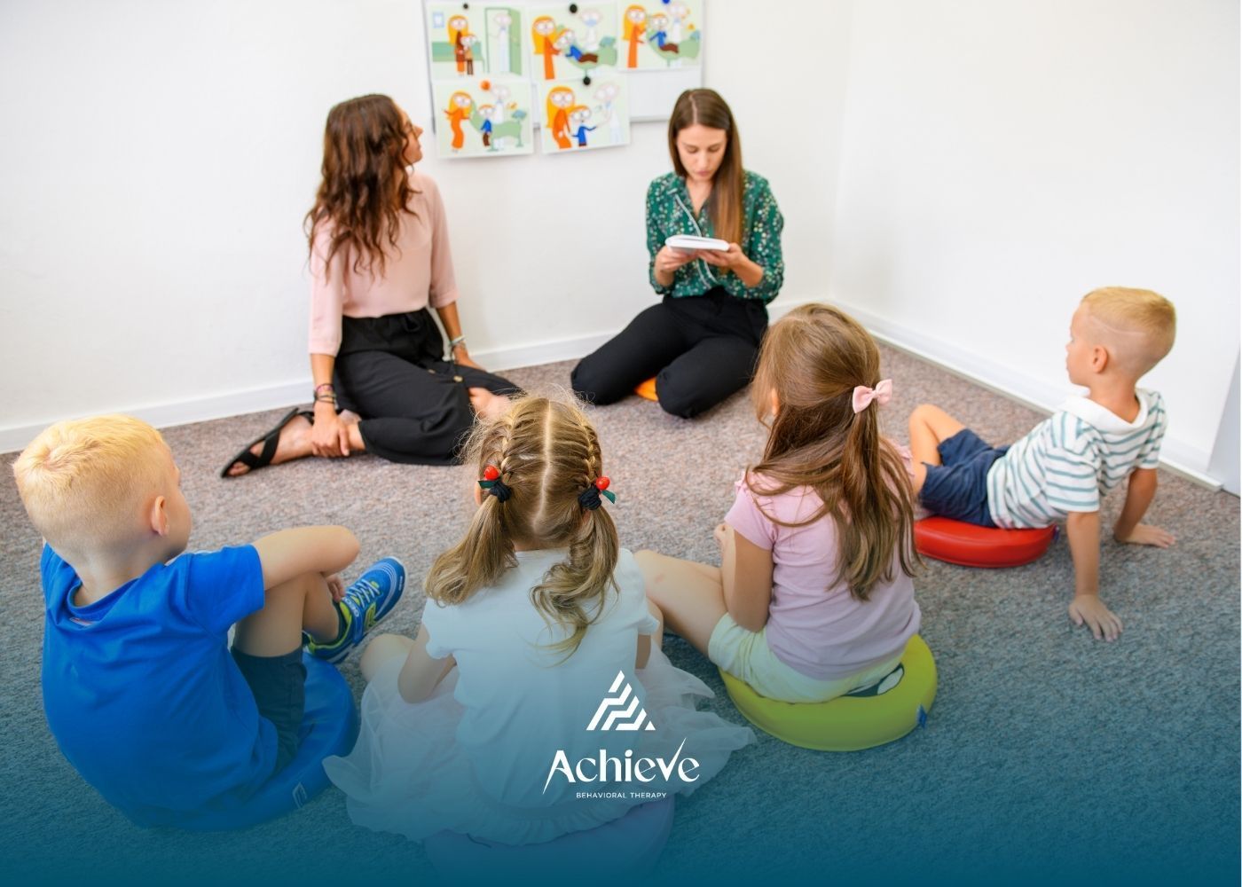 Group of children and adults seated, interacting in a room with a visual aid on the wall.