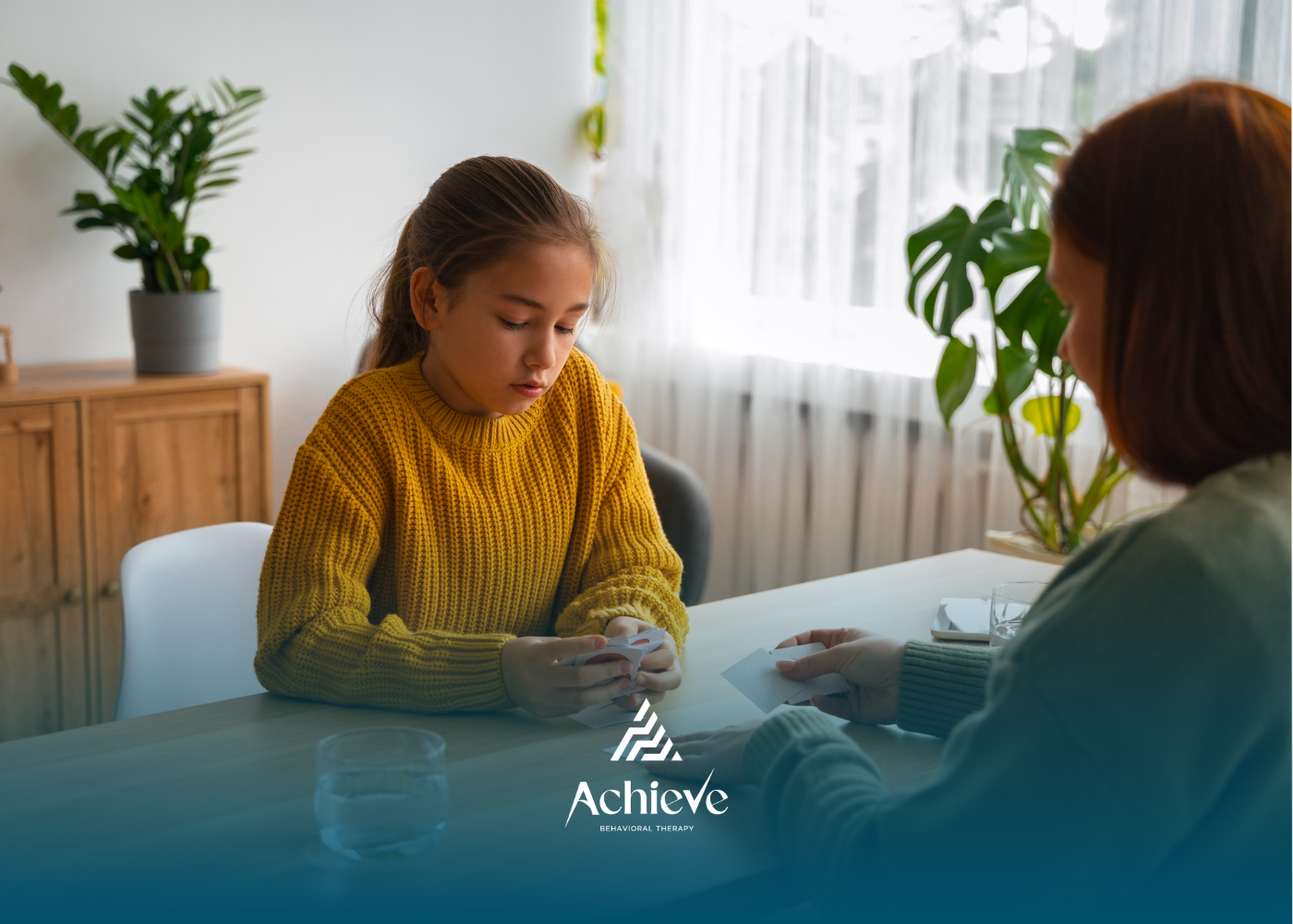 Girl in yellow sweater at table, talking with adult