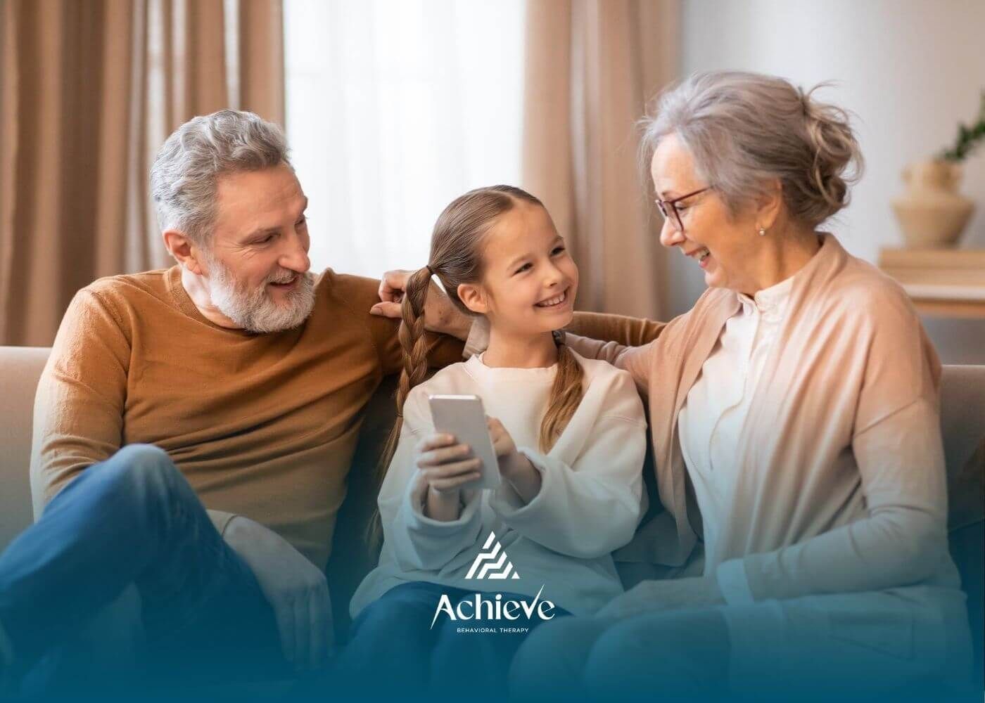 Grandparents and granddaughter with autism sitting together on a couch, smiling.