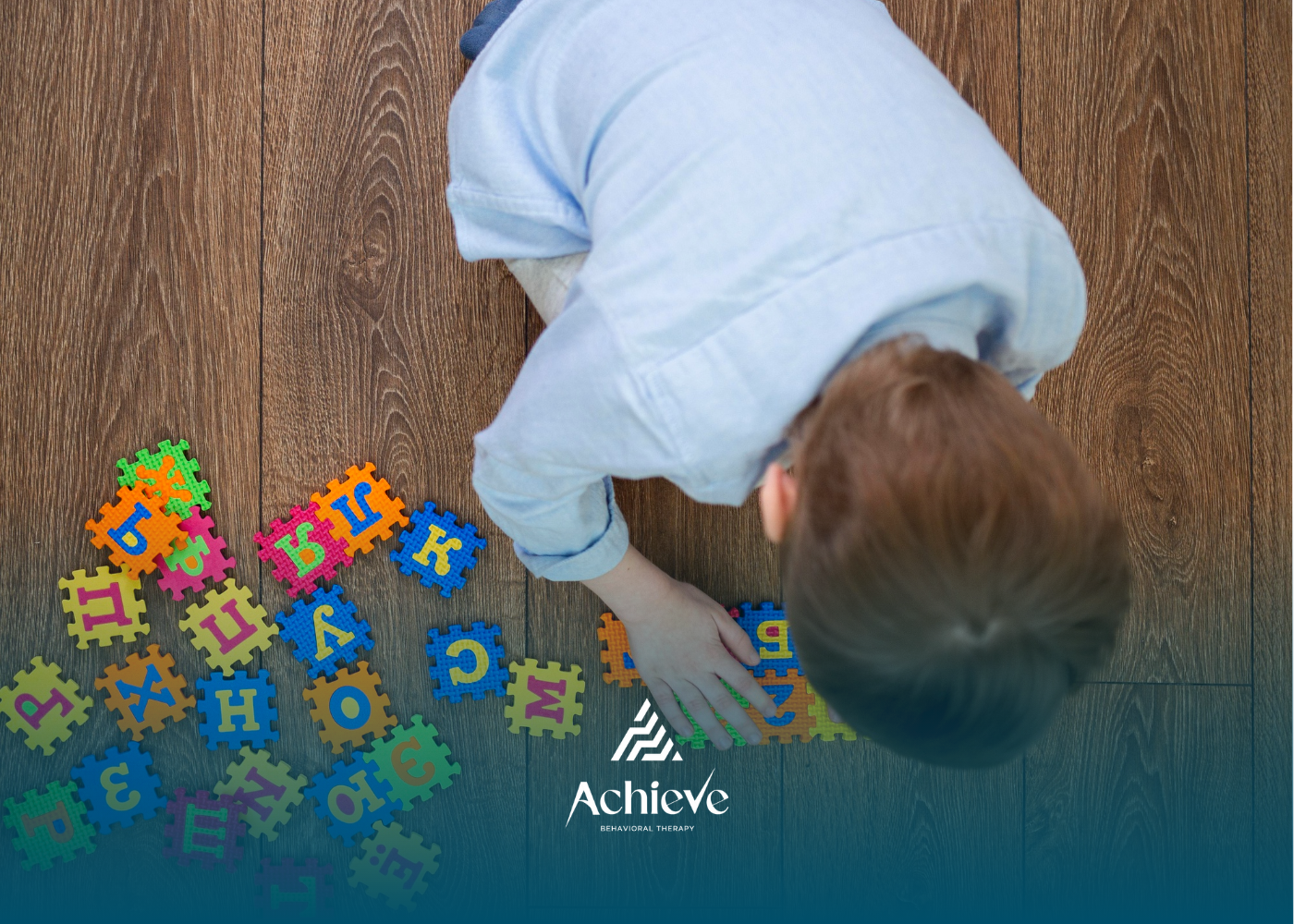 Child arranging colorful alphabet puzzle pieces on a wooden floor.