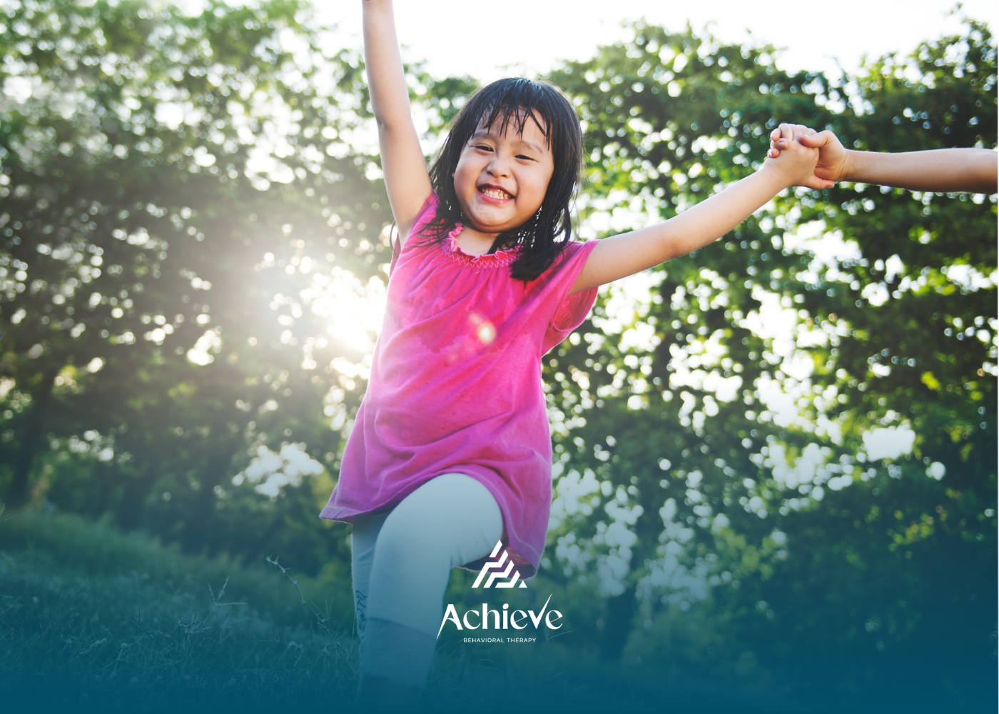 Young girl smiles, arms raised, running in a sunlit field, holding a hand.