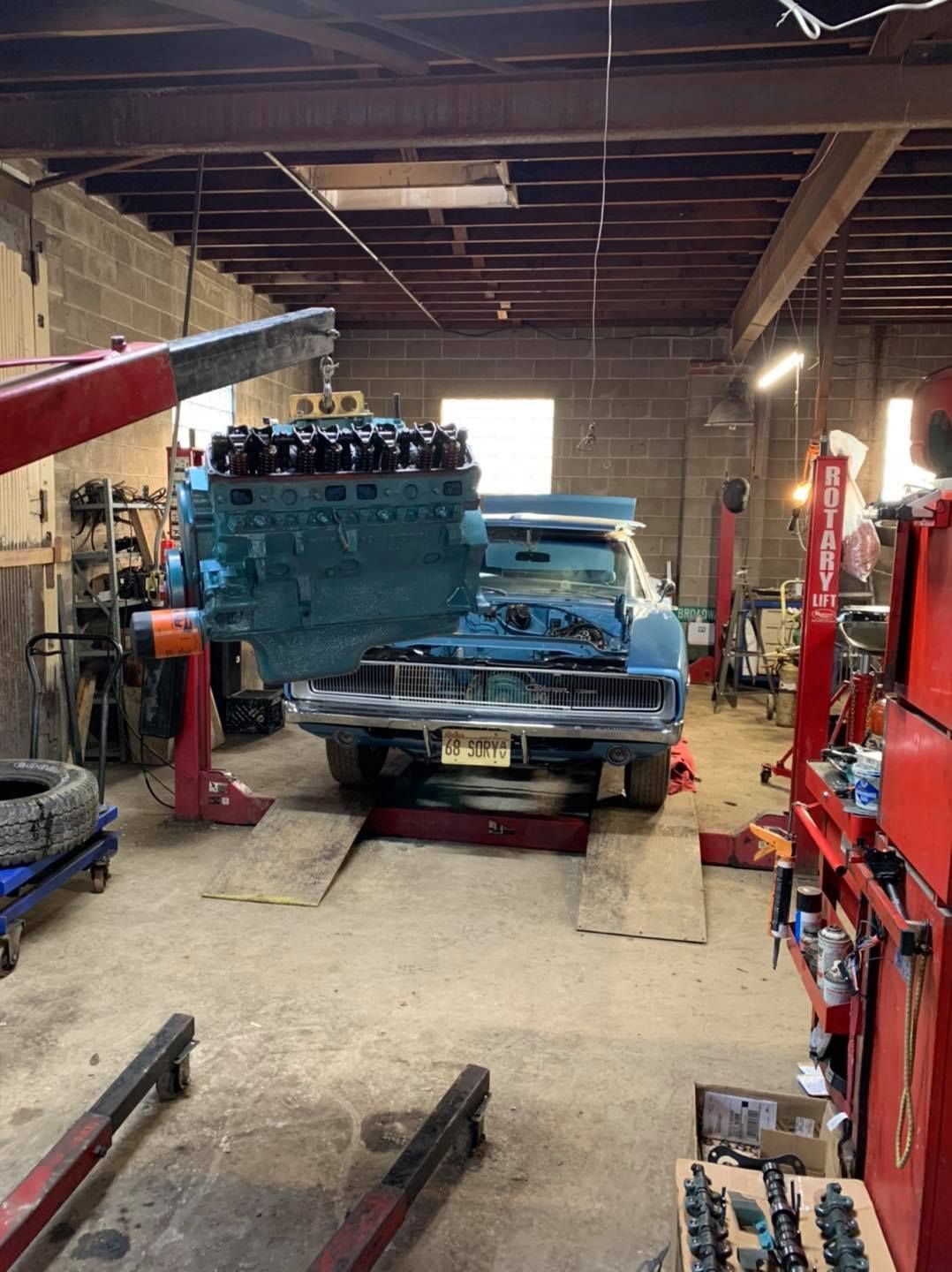 A blue car is being worked on in a garage.
