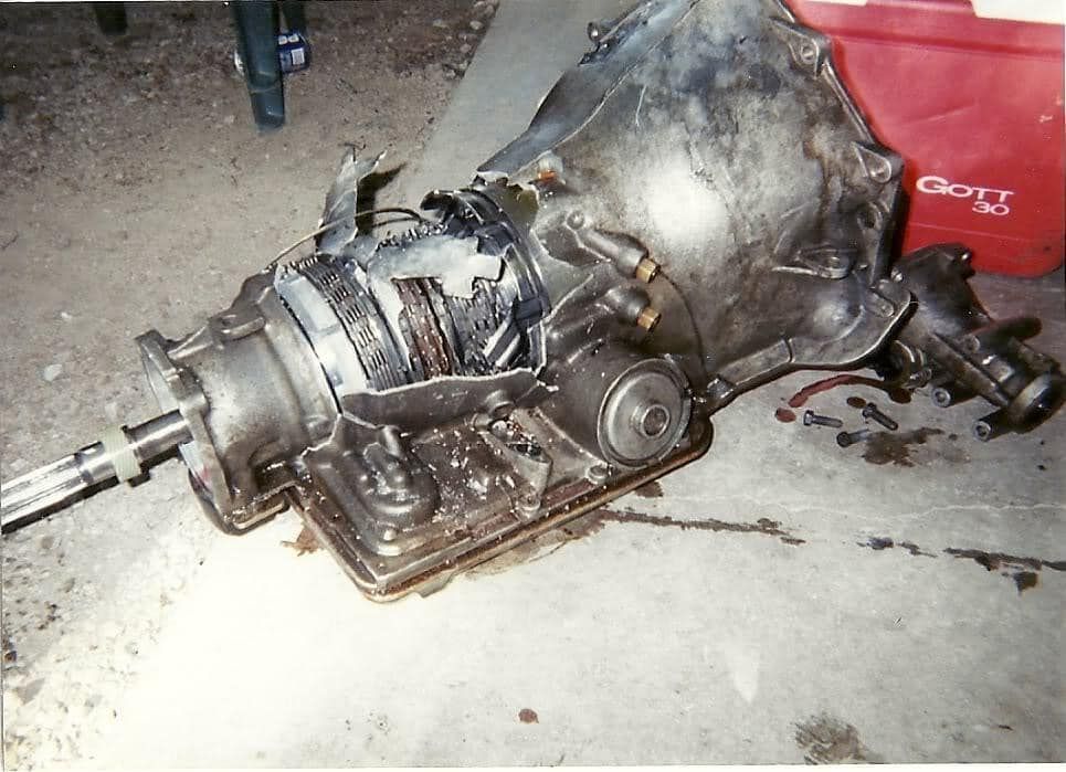 A damaged gearbox with a red cooler in the background