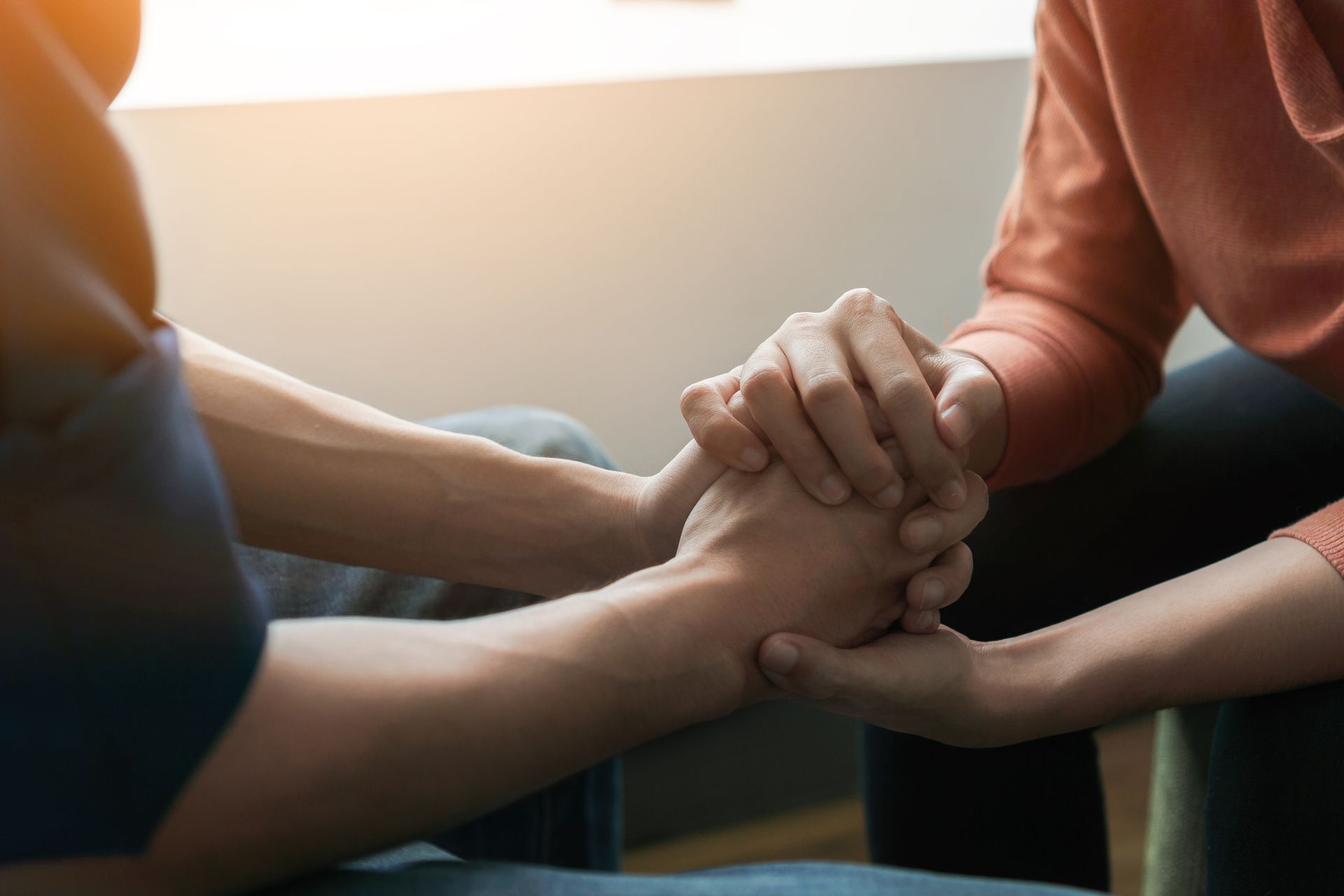 A man and a woman are holding hands while sitting next to each other.