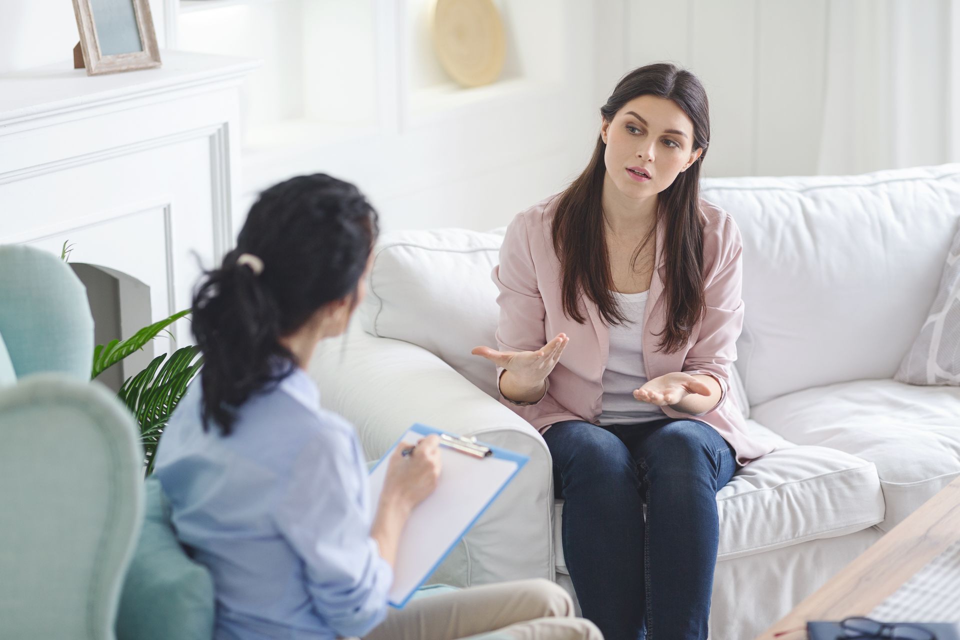 A woman is sitting on a couch talking to a therapist.