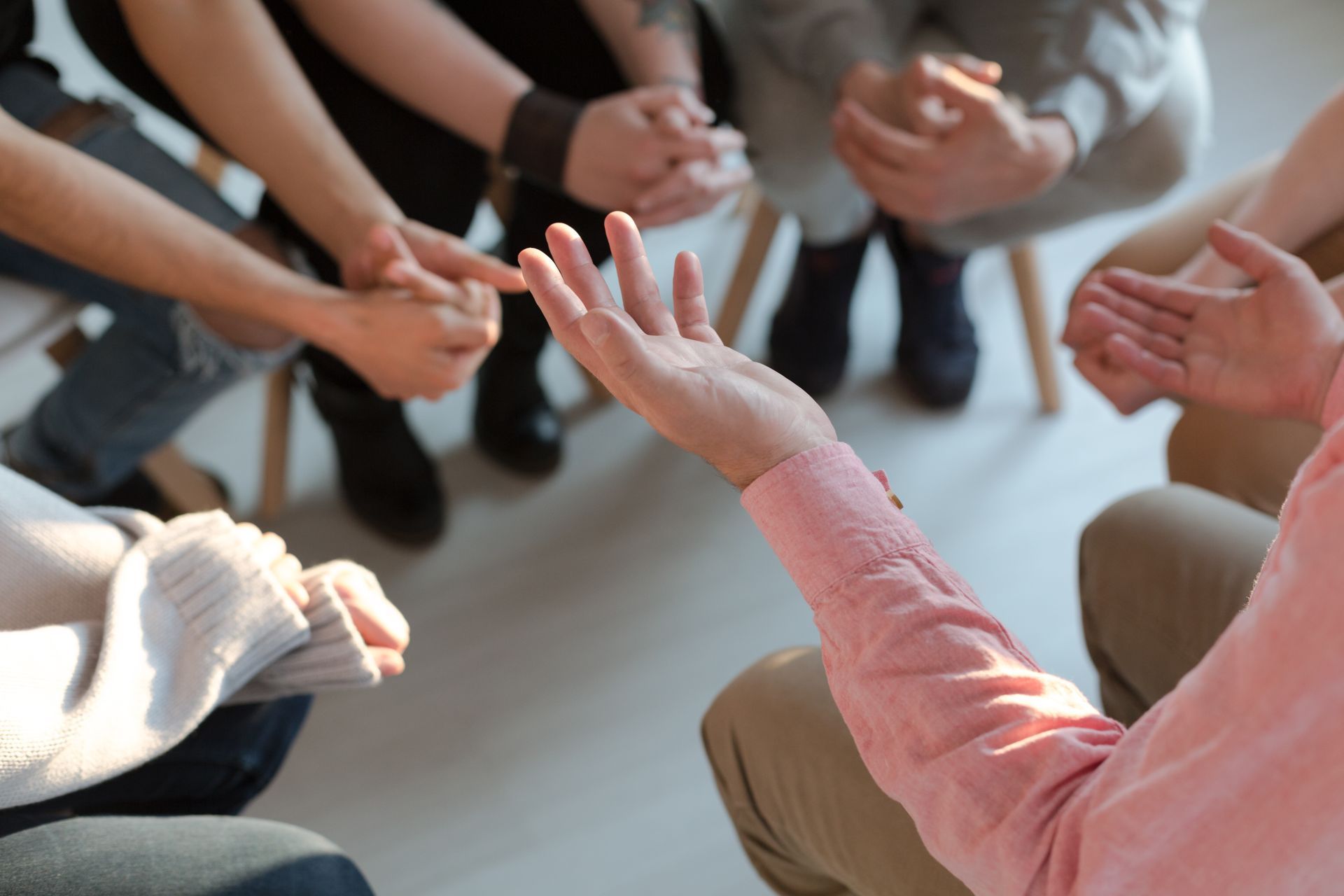 A group of people are sitting in a circle with their hands together.