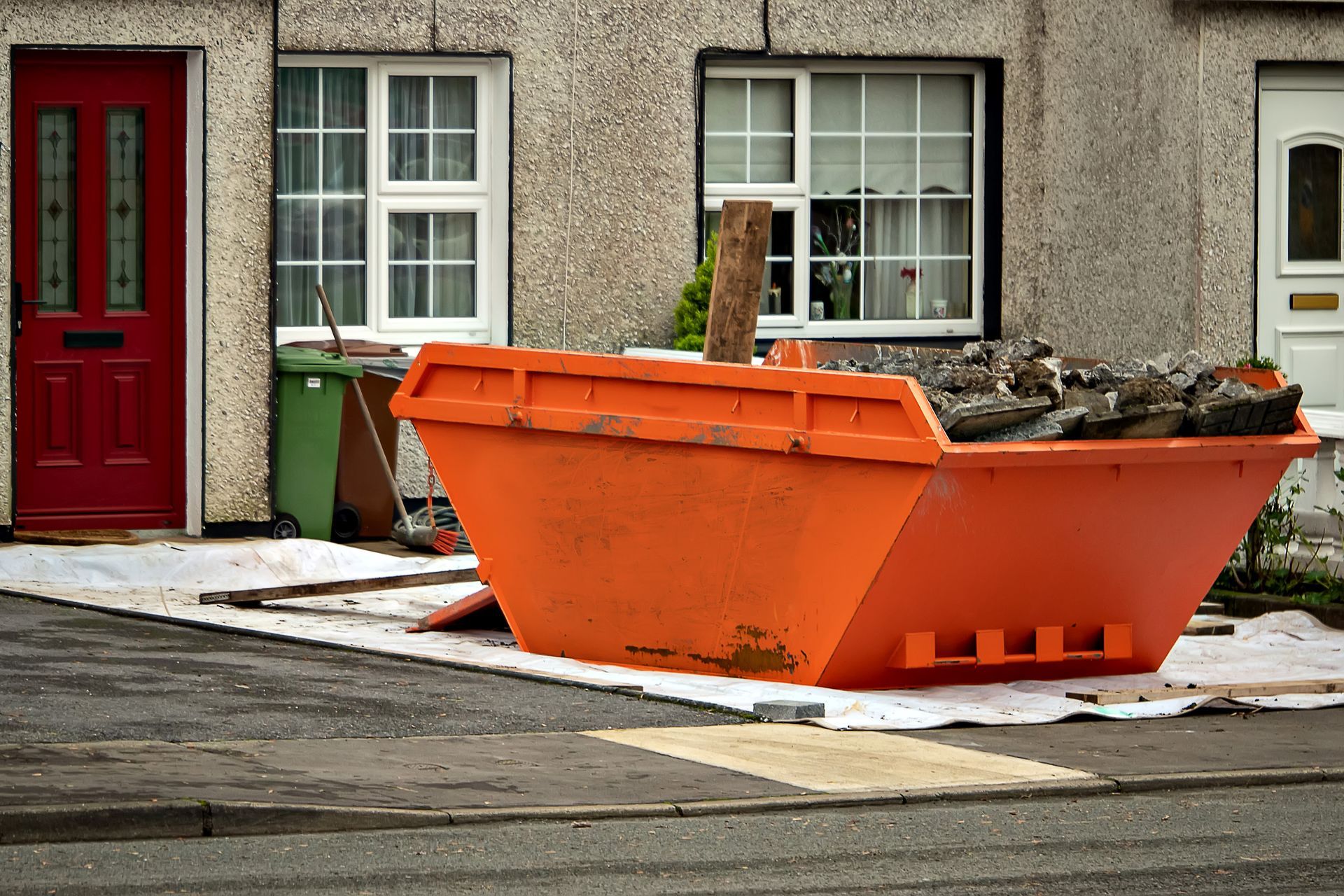 Orange dumpster in front of a house, possibly during renovation.